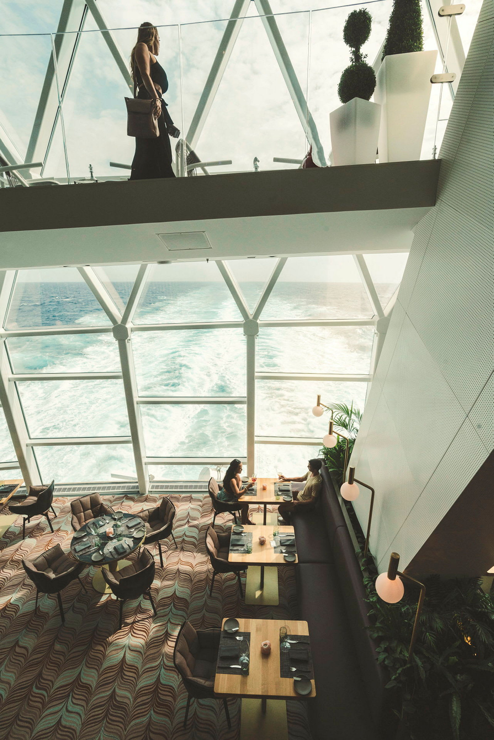 En restaurang med panoramautsikt över havet genom stora fönster. (AI-genererad text)