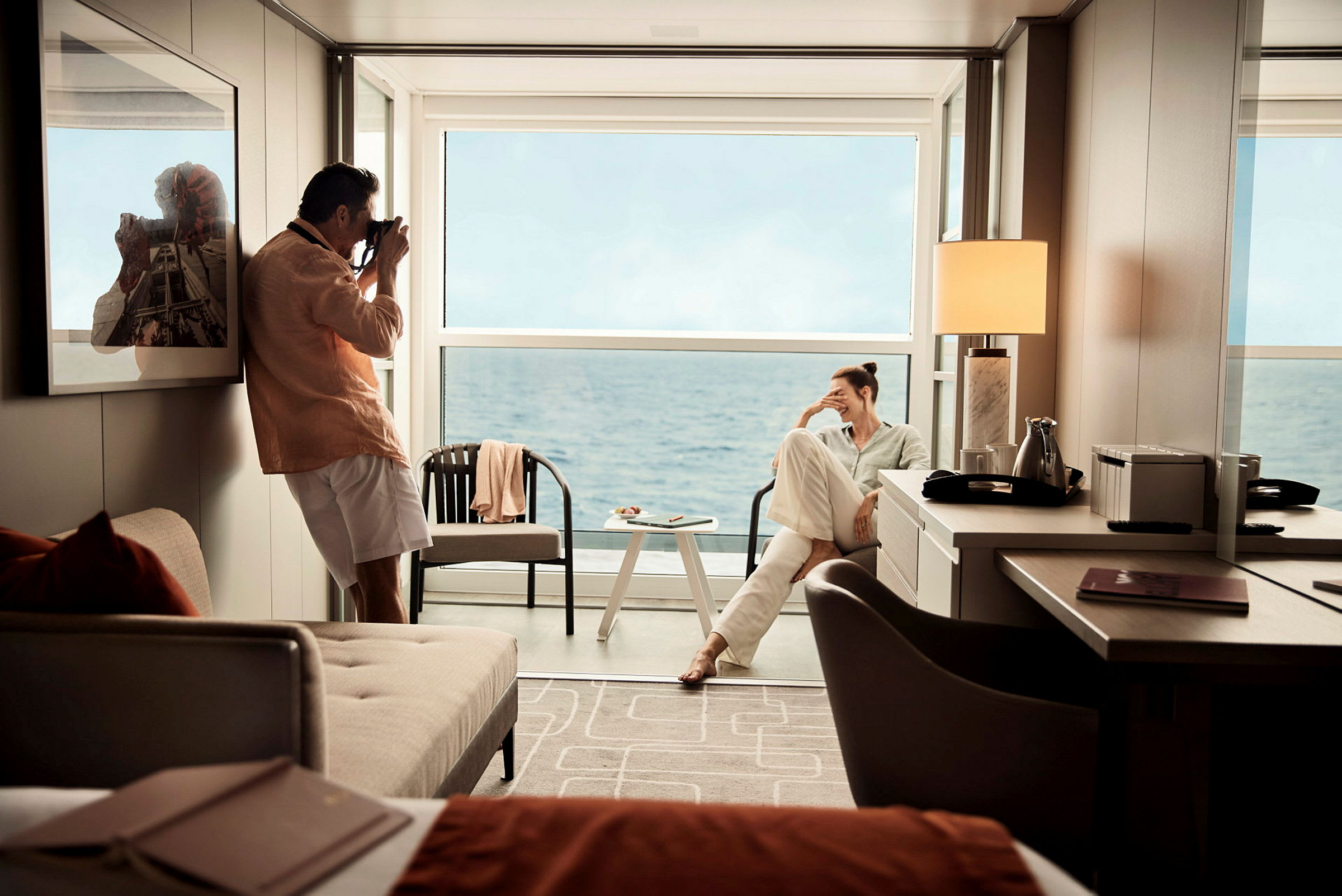 En modern hotellsvit med utsikt över havet, där möbler inkluderar en soffa, ett bord och en stol. (AI-genererad text)