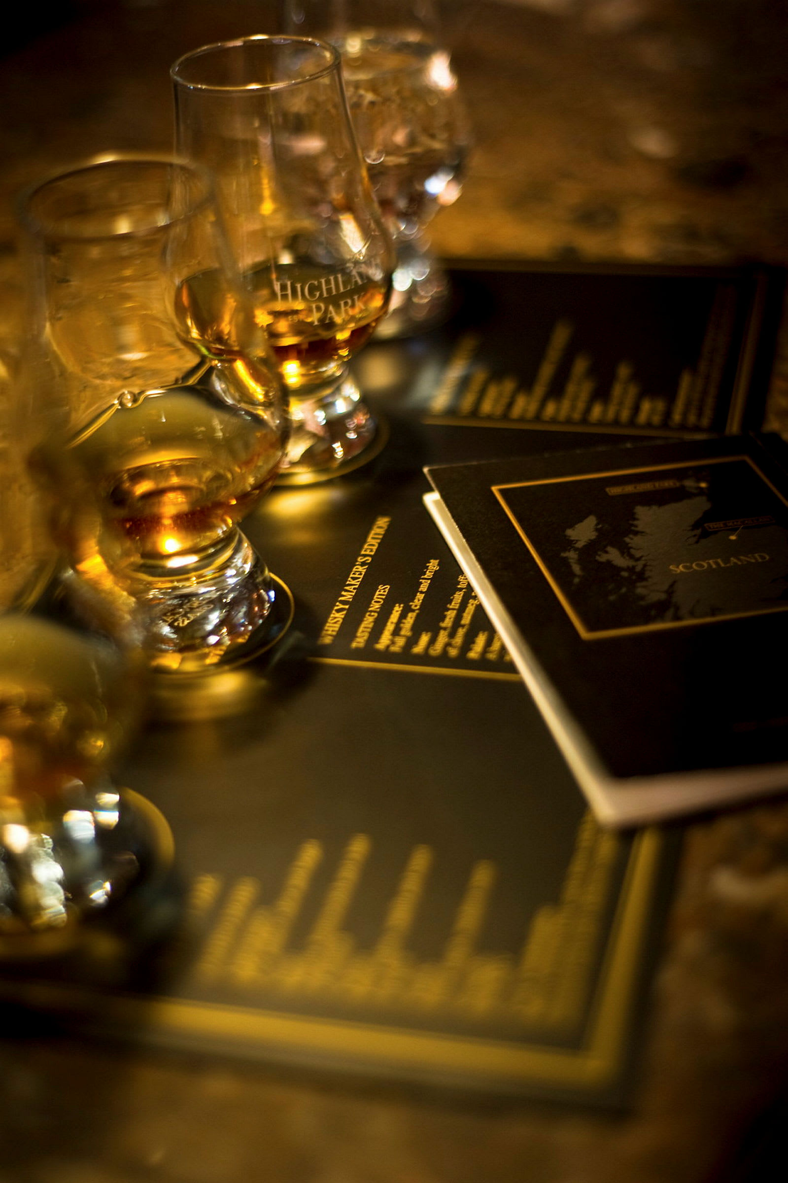 Flera glas med whisky står på ett bord med broschyrer i bakgrunden. (AI-genererad text)