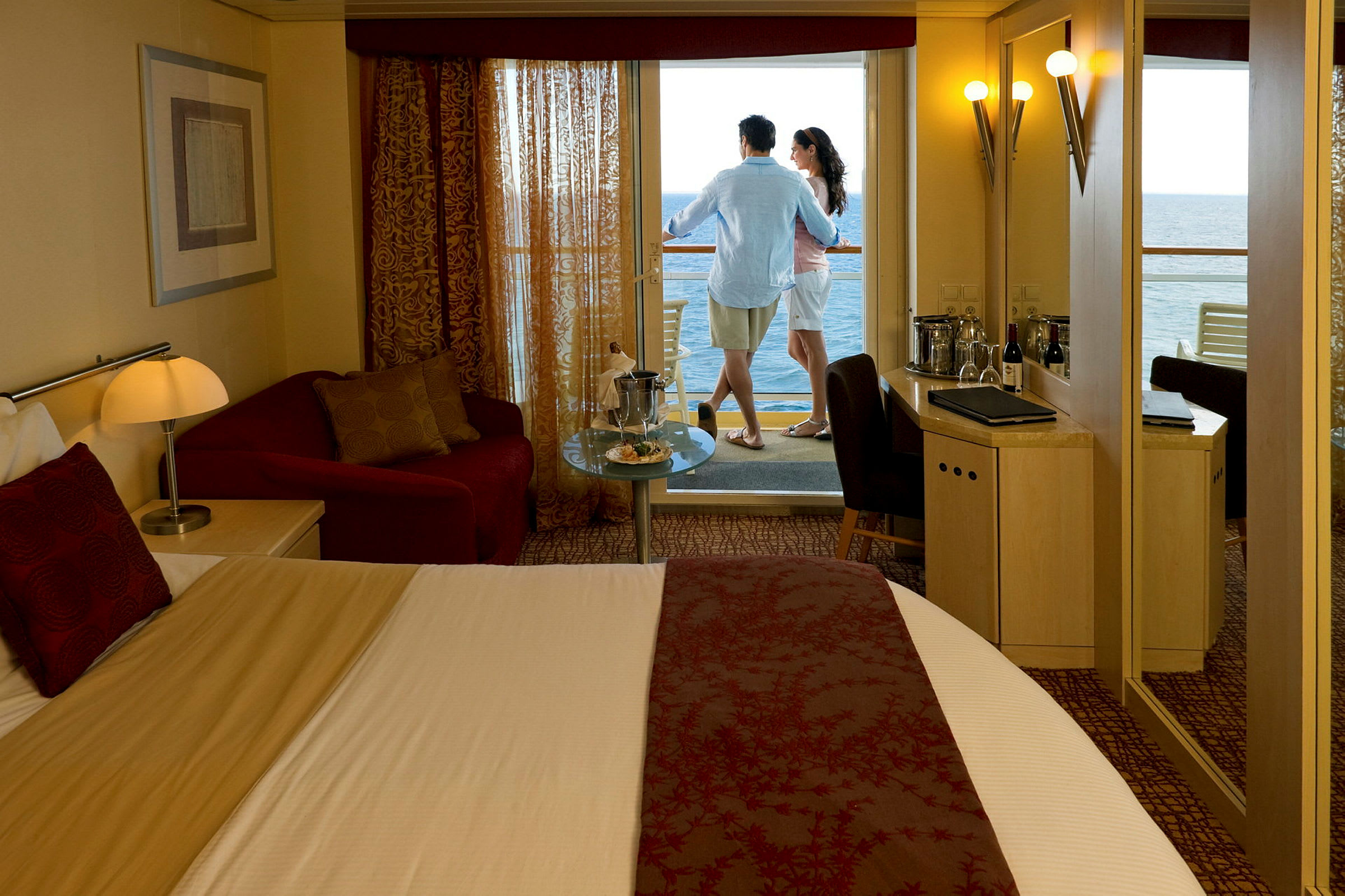 Ett hotellrum med en stor säng, sittmöbler och en balkong med havsutsikt. (AI-genererad text)