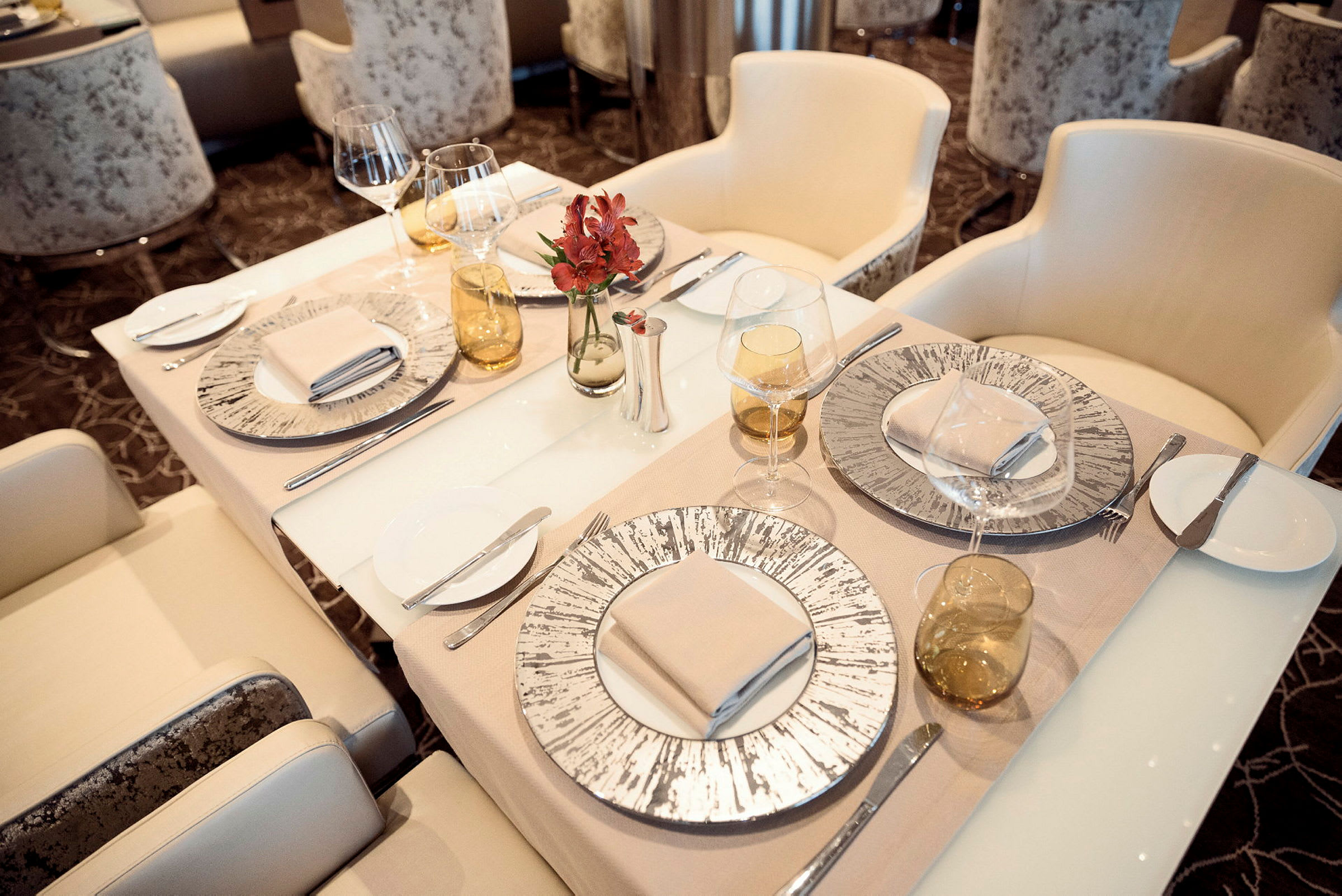 Ett elegant dukat bord med tallrikar, glas, bestick och en blomma som dekoration. (AI-genererad text)