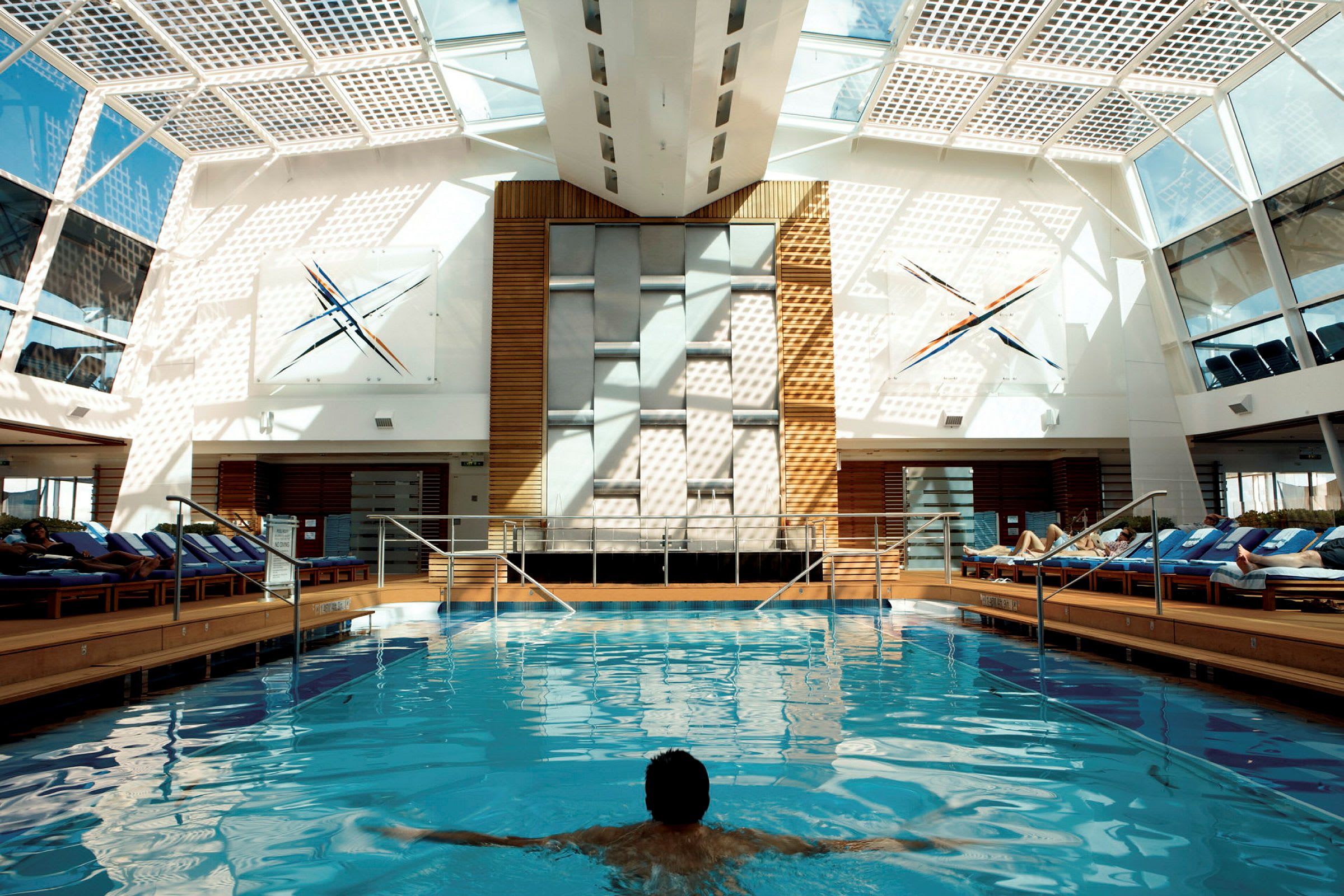 Inomhuspool med sittplatser och glasväggar. (AI-genererad text)