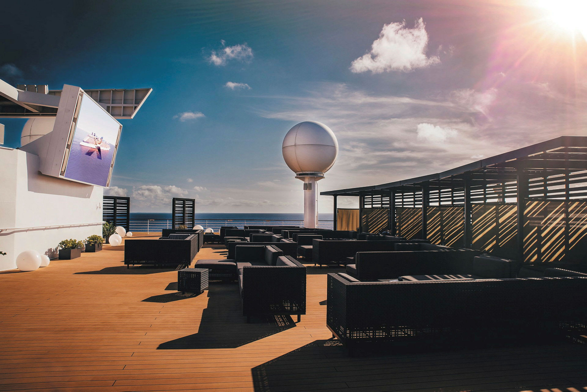 En solterrass med sittmöbler och en stor sfärisk struktur i bakgrunden. (AI-genererad text)