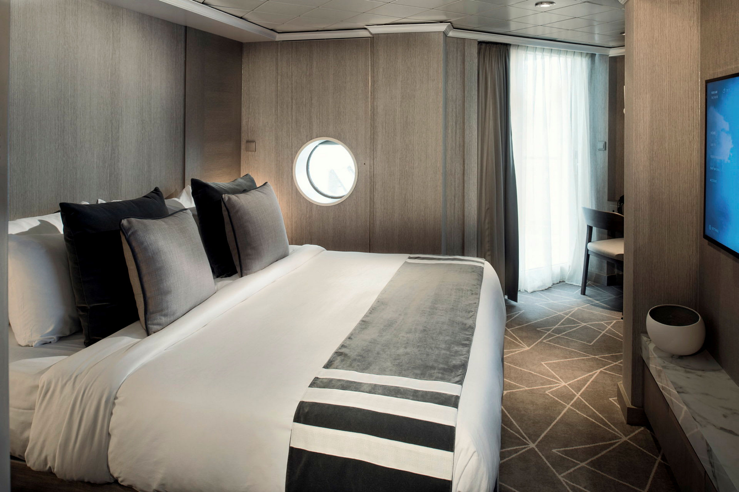 Moderna hotellrum med en stor säng, runda fönster och elegant inredning. (AI-genererad text)