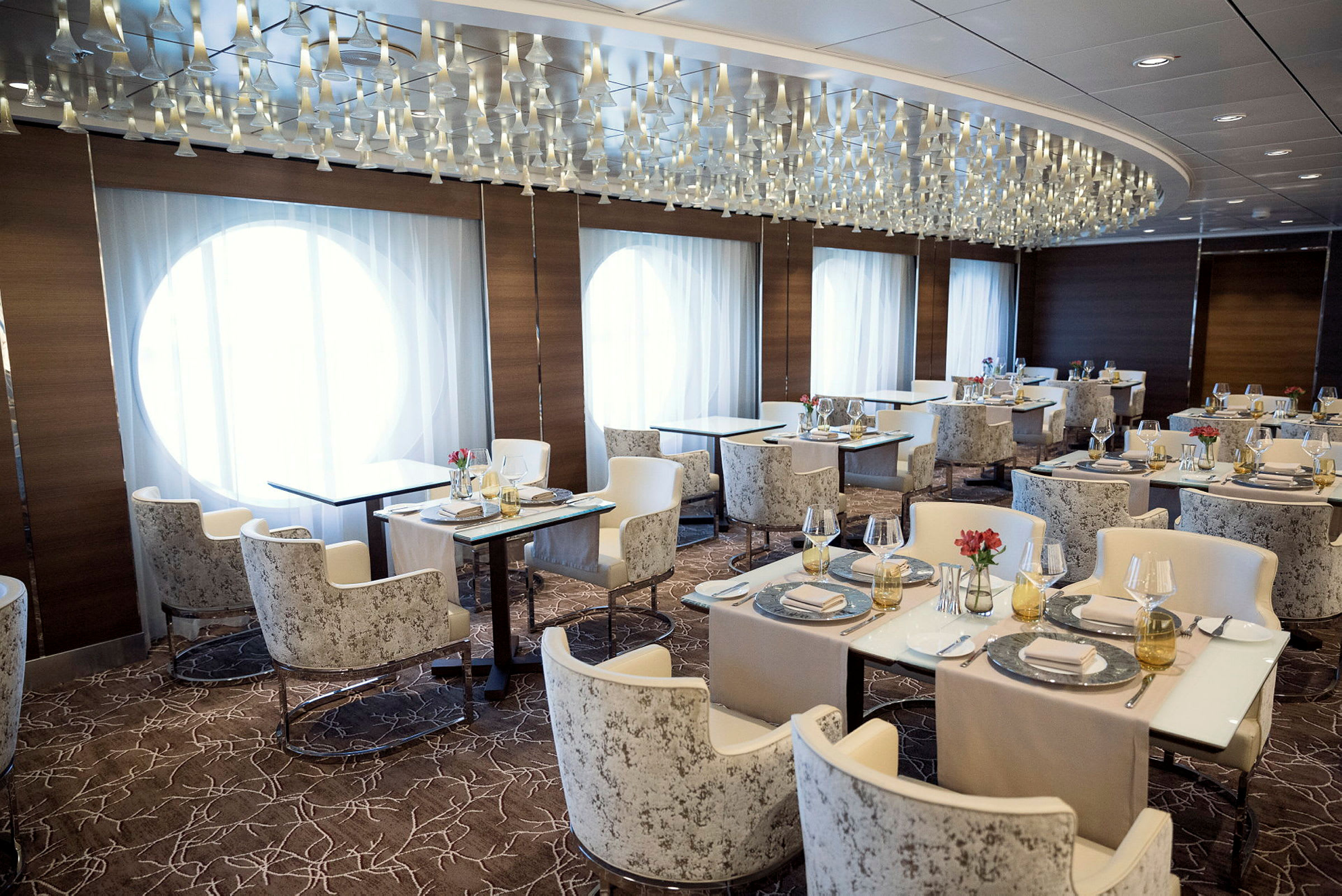 En elegant restaurang med vit inredning, stora fönster och stämningsfull belysning. (AI-genererad text)