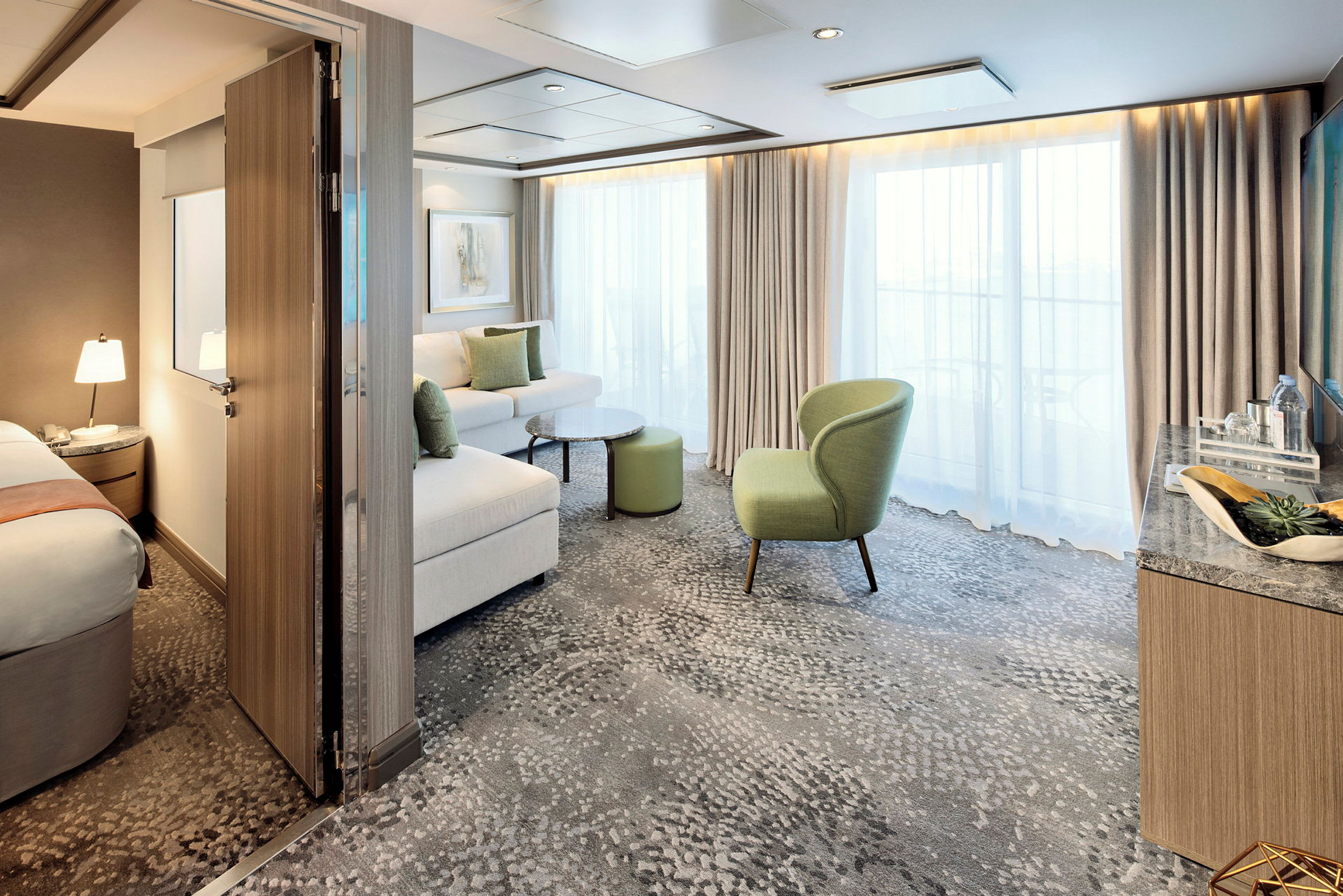 Hotellrum med öppet område, soffa, fåtölj och stora fönster. (AI-genererad text)