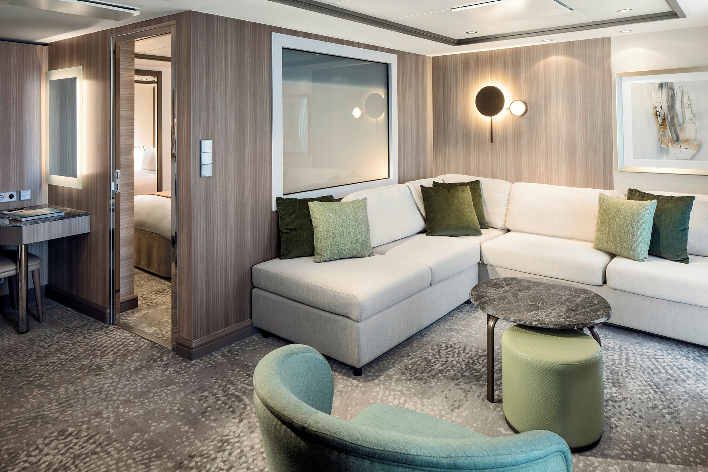 Ett modern hotellrum med en L-formad soffa, gröna kuddar, ett litet bord och en stolsinredning. (AI-genererad text)