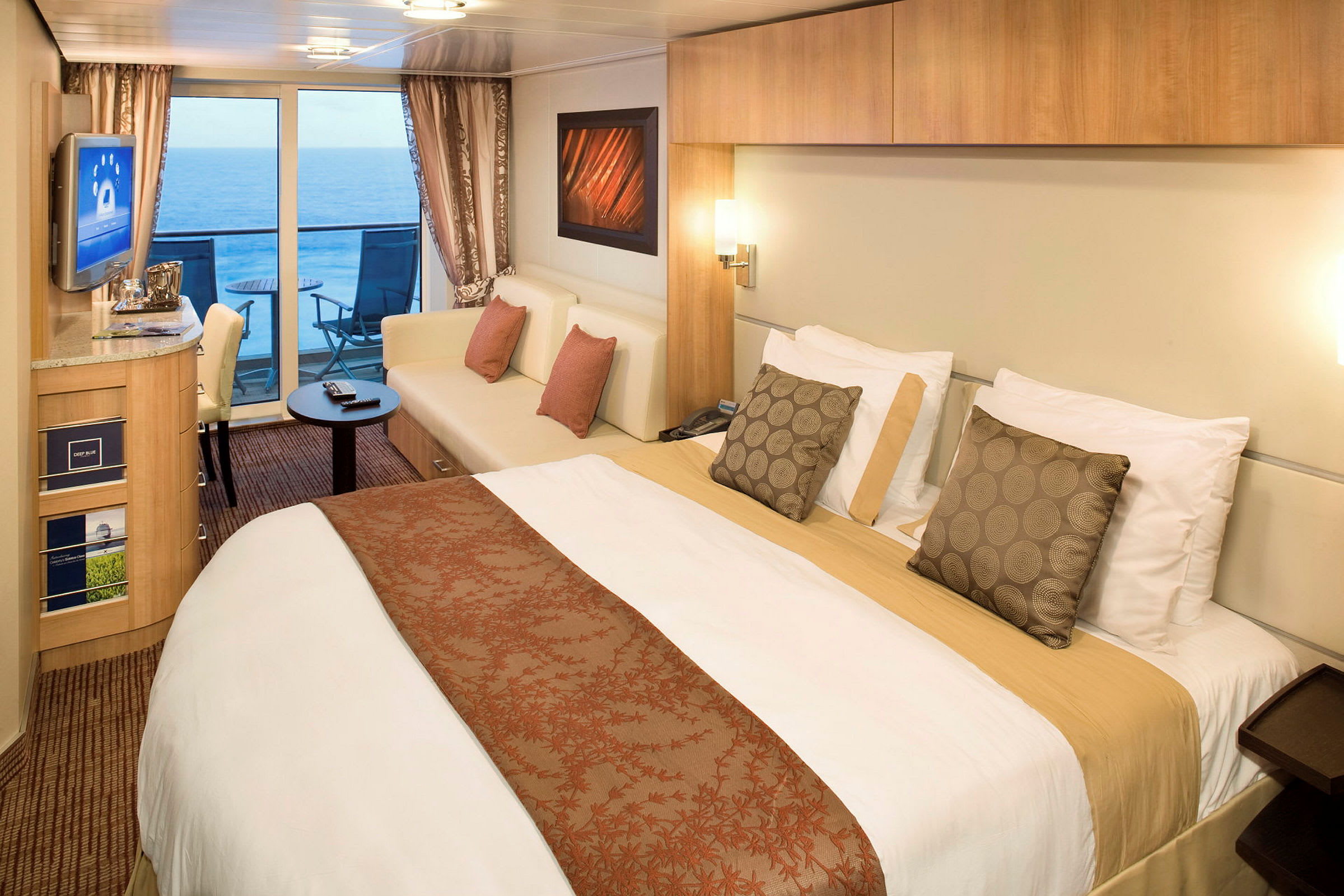 Ett hotellrum med en stor säng, sittgrupp och en balkong med utsikt över havet. (AI-genererad text)
