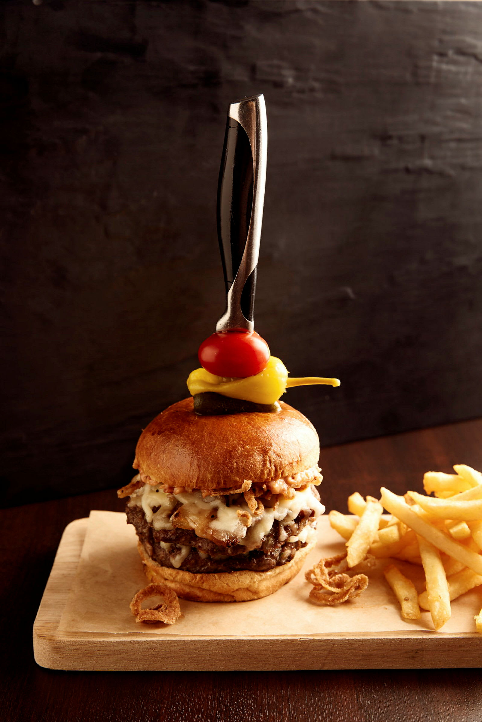 En hamburgare med pommes frites på en träbricka. (AI-genererad text)