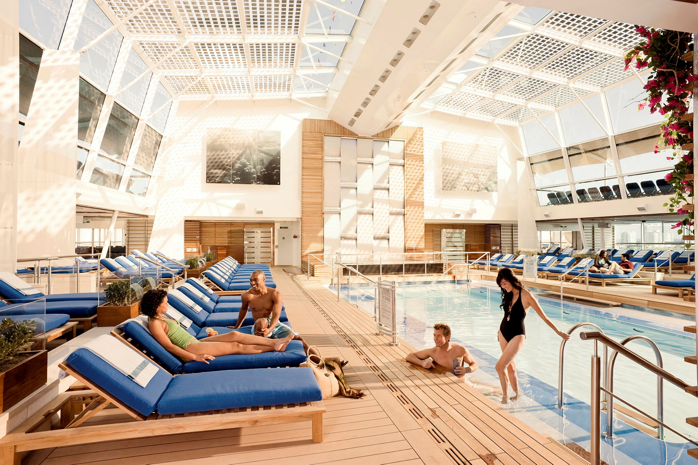En inomhuspool omgiven av solstolar och ljus arkitektur. (AI-genererad text)