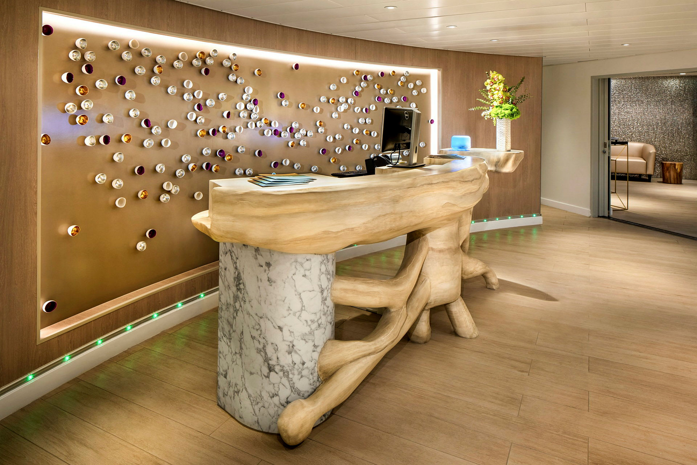 En reception med ett bord i trä och marmor samt en dekorerad vägg bakom. (AI-genererad text)