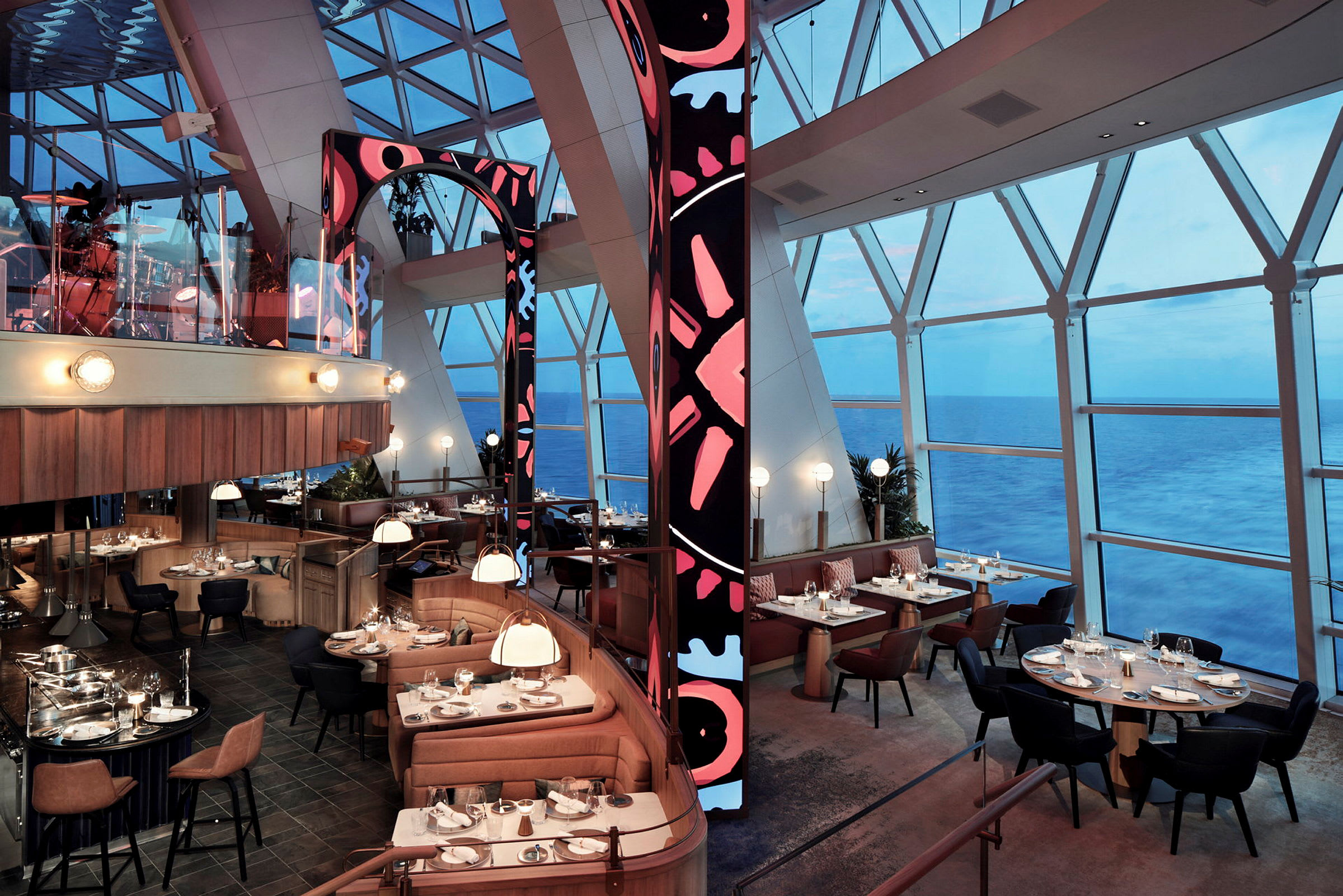 En elegant restaurang med panoramavy över havet genom stora fönster. Inredningen består av komfortabla sittplatser och modern stil. (AI-genererad text)