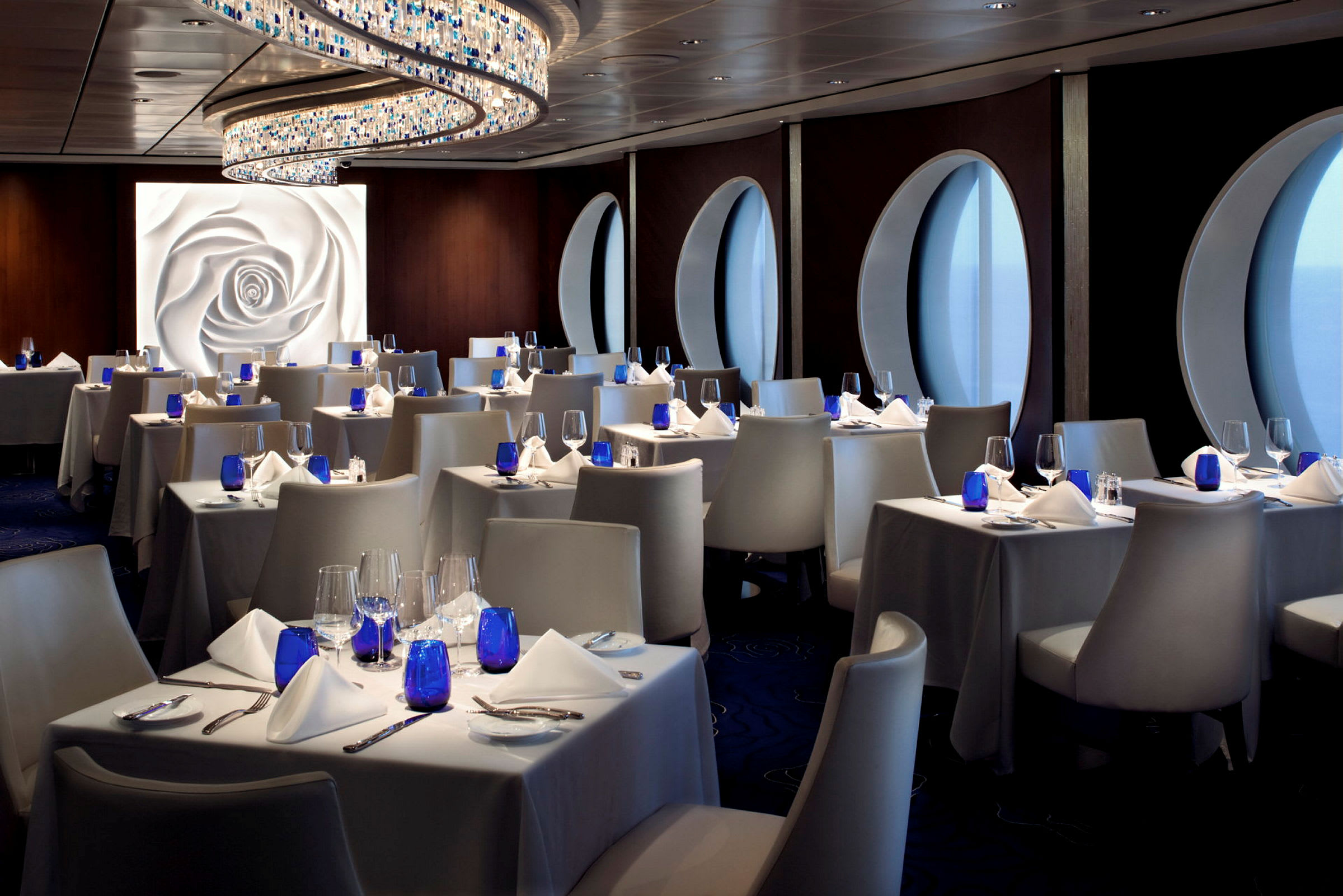 En elegant restaurang med vita borddukar, blå glas och moderna stolar. (AI-genererad text)