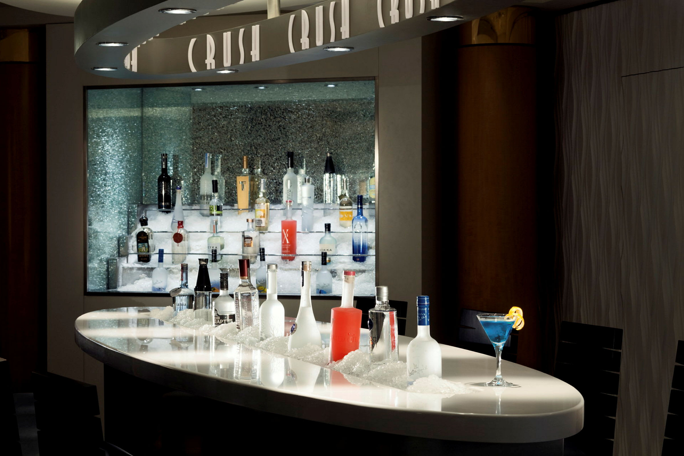 Bar med en rad alkoholflaskor på is, samt en blå cocktail. (AI-genererad text)