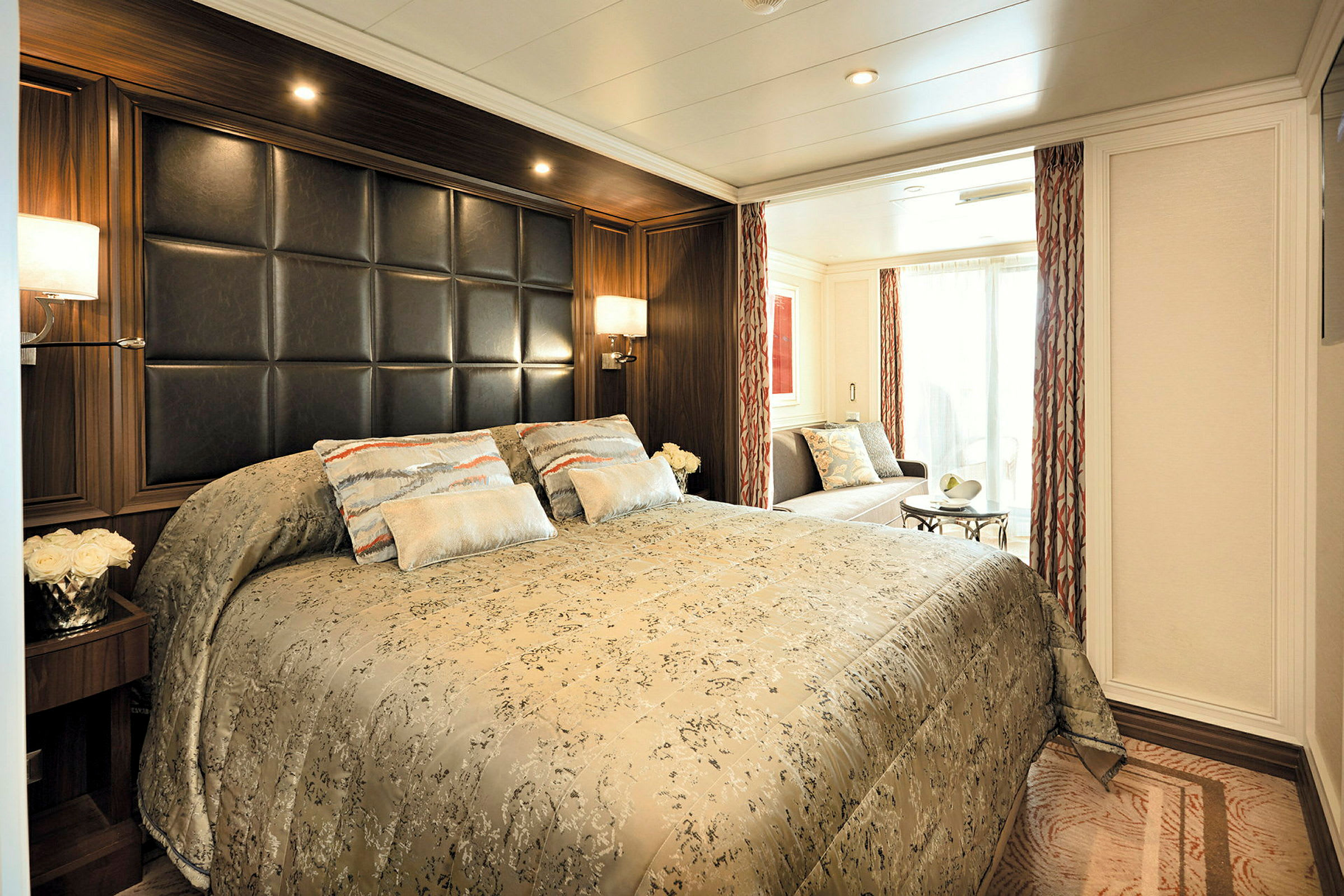 Ett elegant hotellrum med en stor säng, dekorativa kuddar och en sittgrupp nära ett stort fönster. (AI-genererad text)