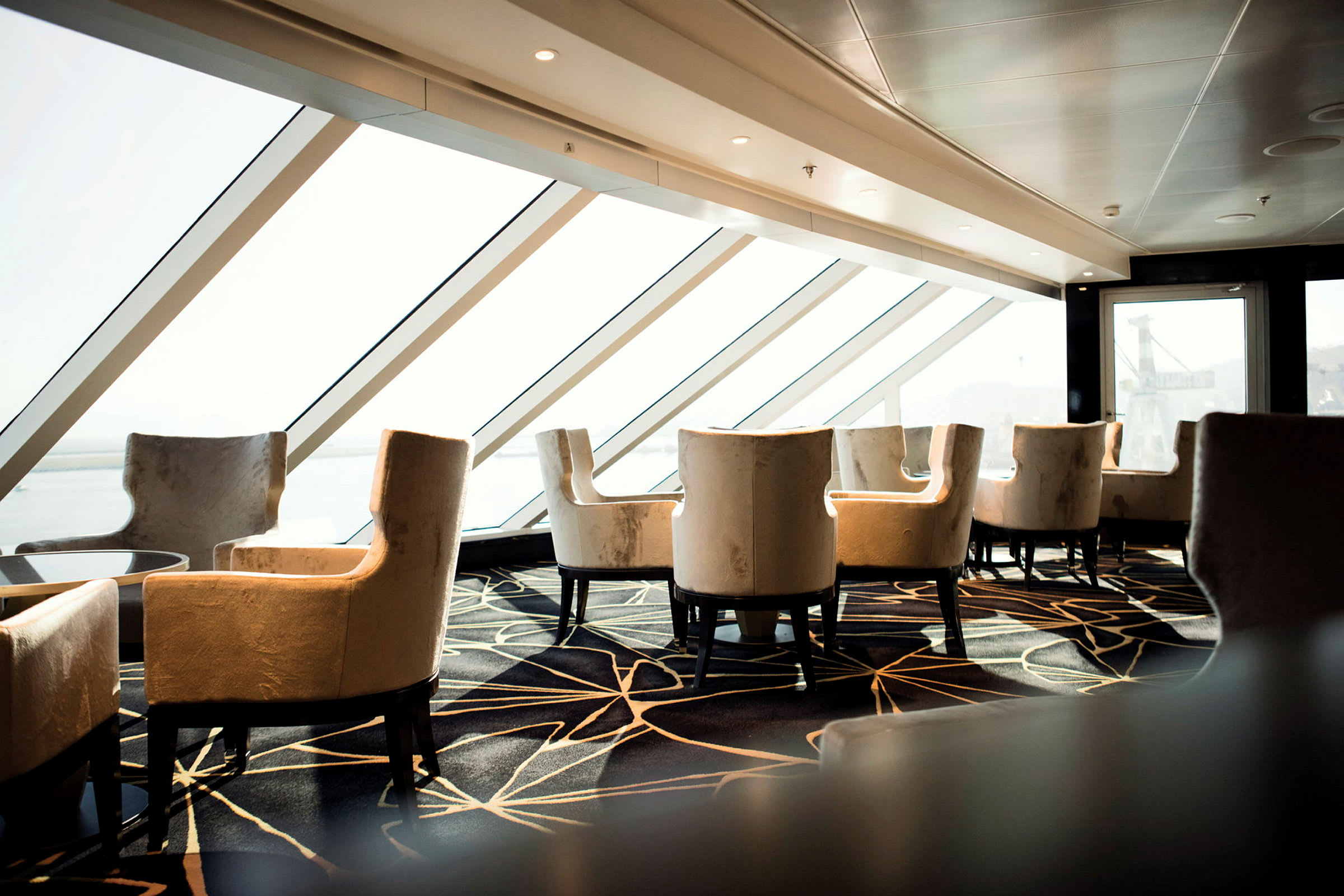 Interiör av en modern loungemiljö med vadderade stolar och stora fönster. (AI-genererad text)