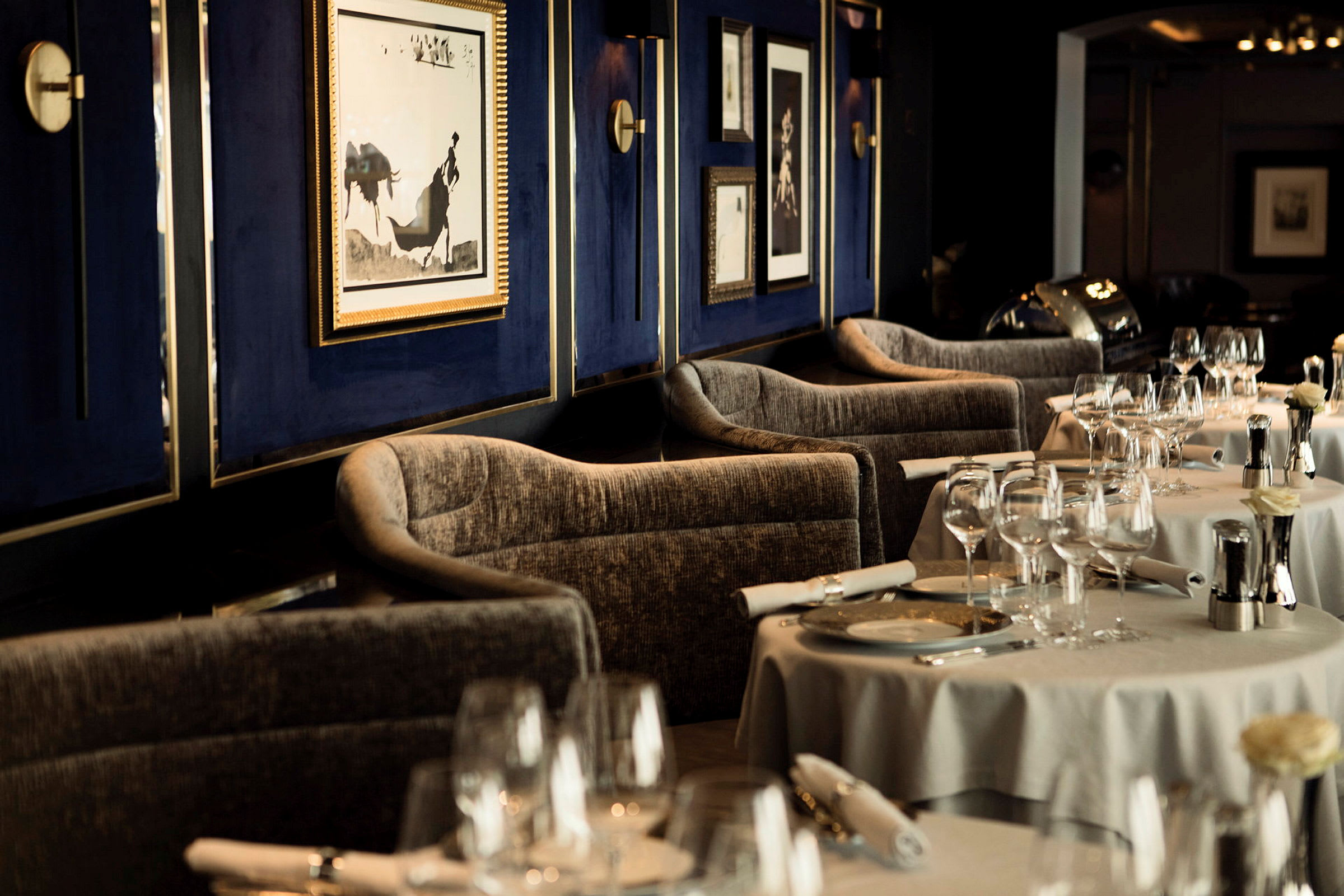 Interiör av en elegant restaurang med dukade bord och konstverk på väggen. (AI-genererad text)