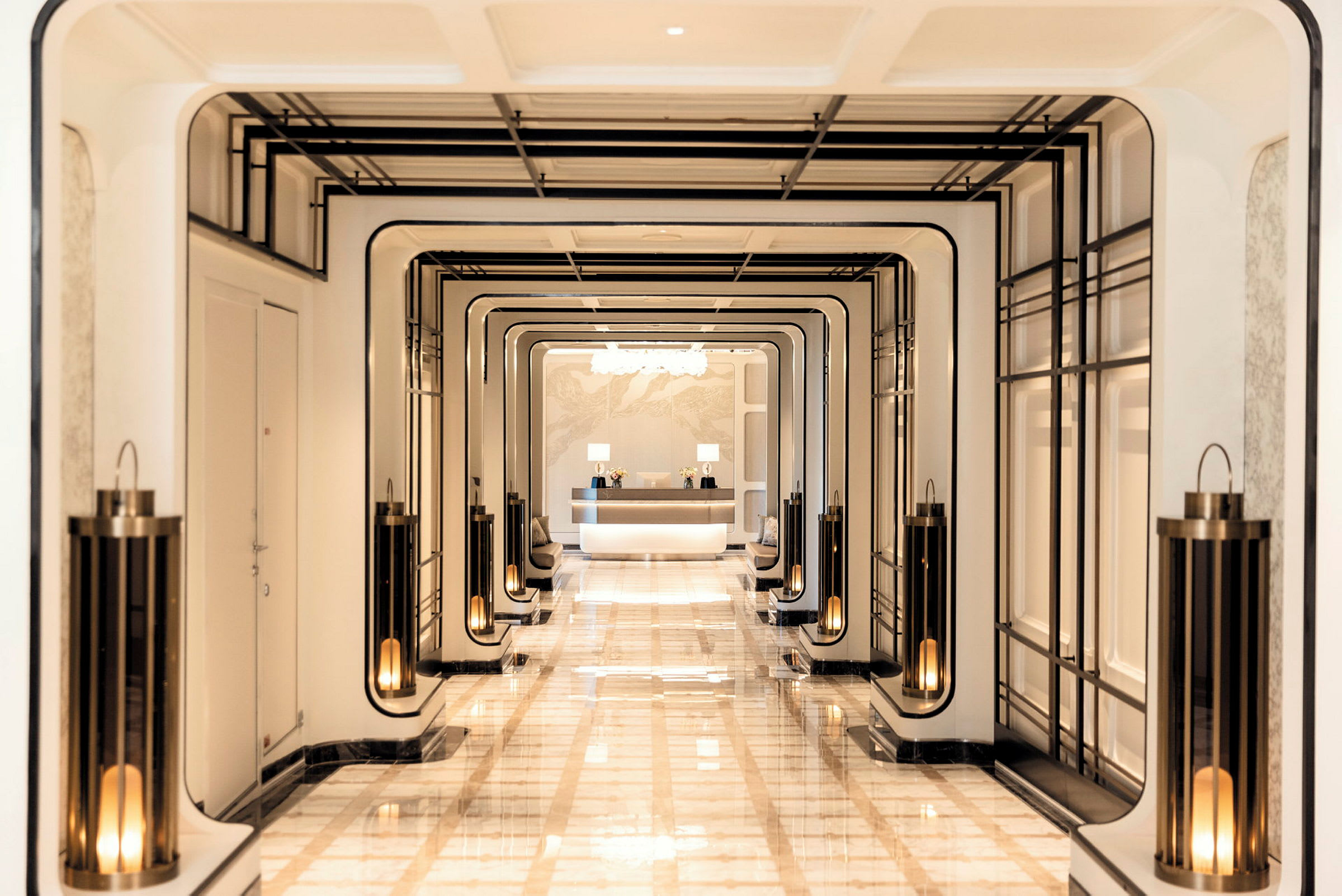 Hotellkorridor med eleganta ljuslyktor och receptionsdisk i bakgrunden. (AI-genererad text)