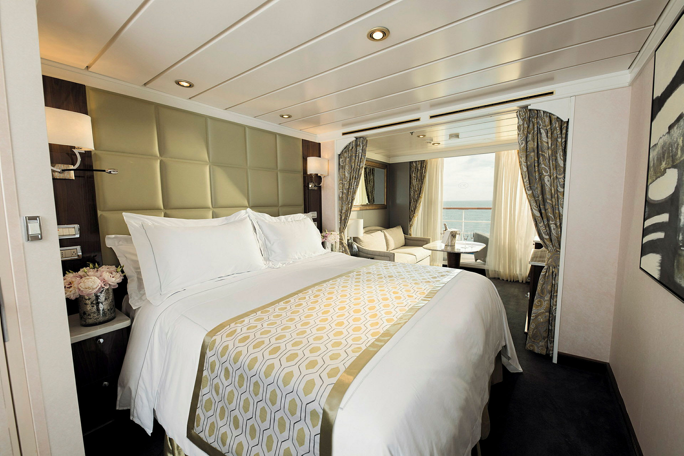 Ett lyxigt hotellrum med en stor säng, sittgrupp och utsikt över havet. (AI-genererad text)