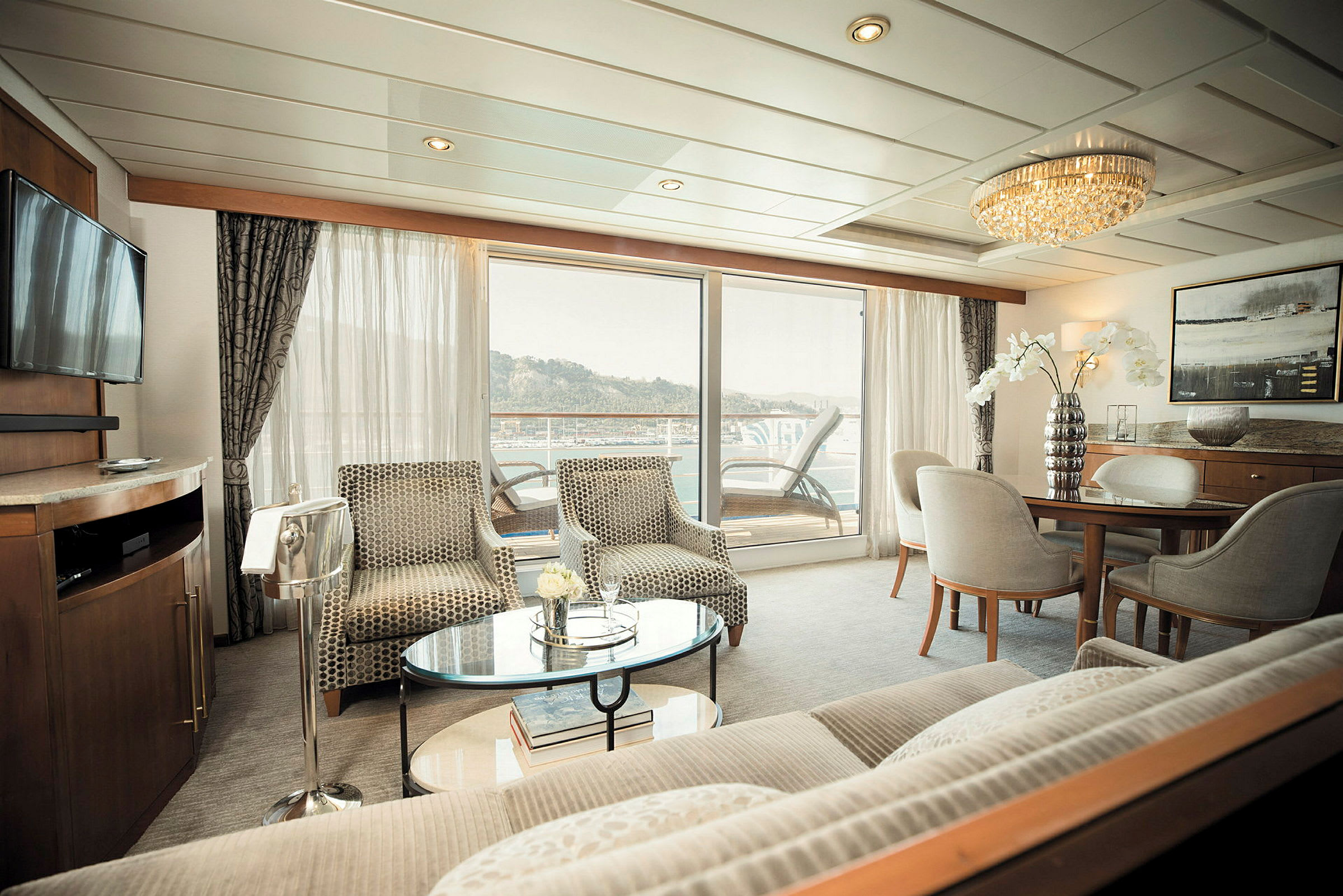 Ett modernt hotellrum med sittgrupp, matbord och utsikt mot en balkong. (AI-genererad text)