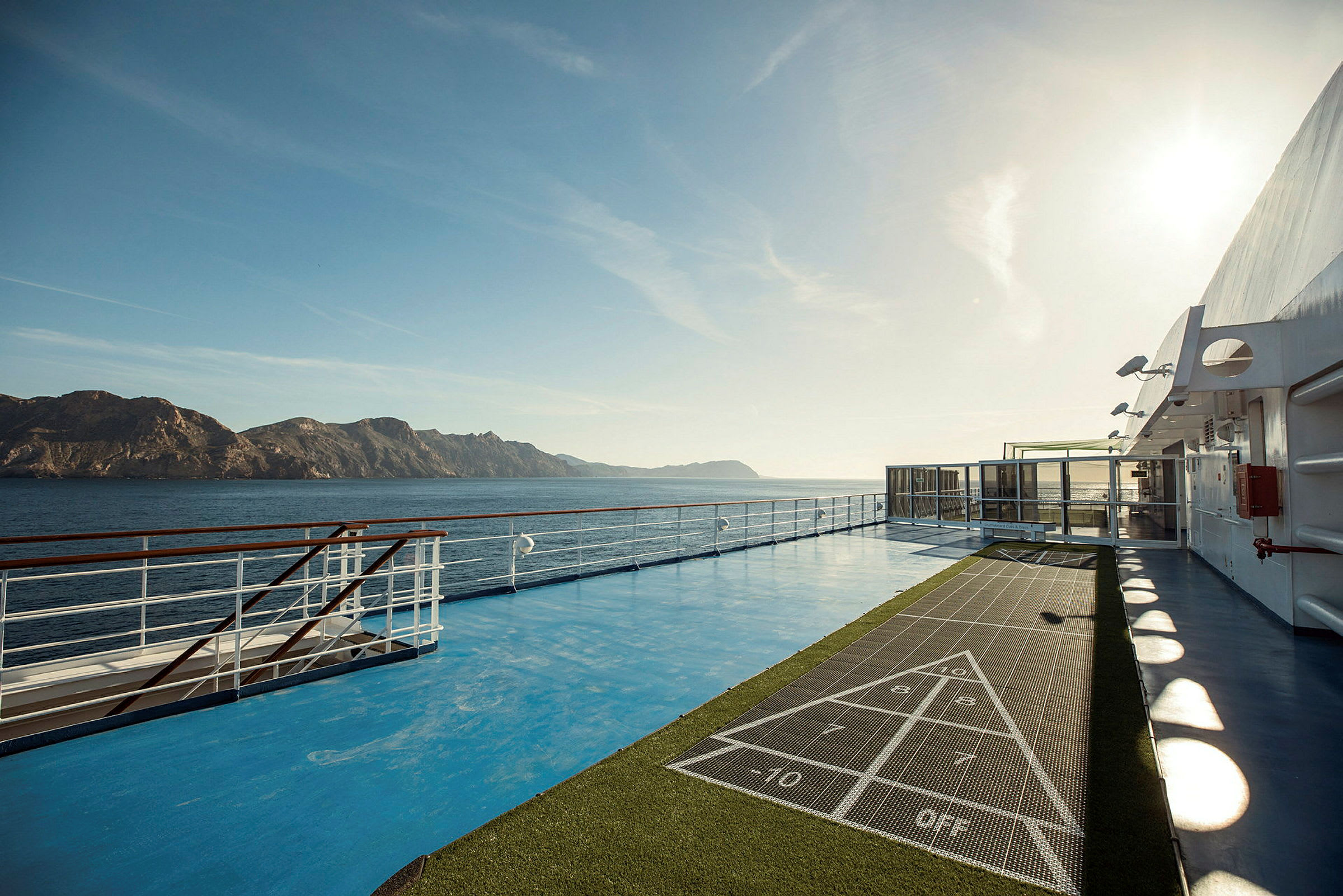 Bild av kryssningsfartygets däck, med ett område för shuffleboard och havsutsikt. (AI-genererad text)