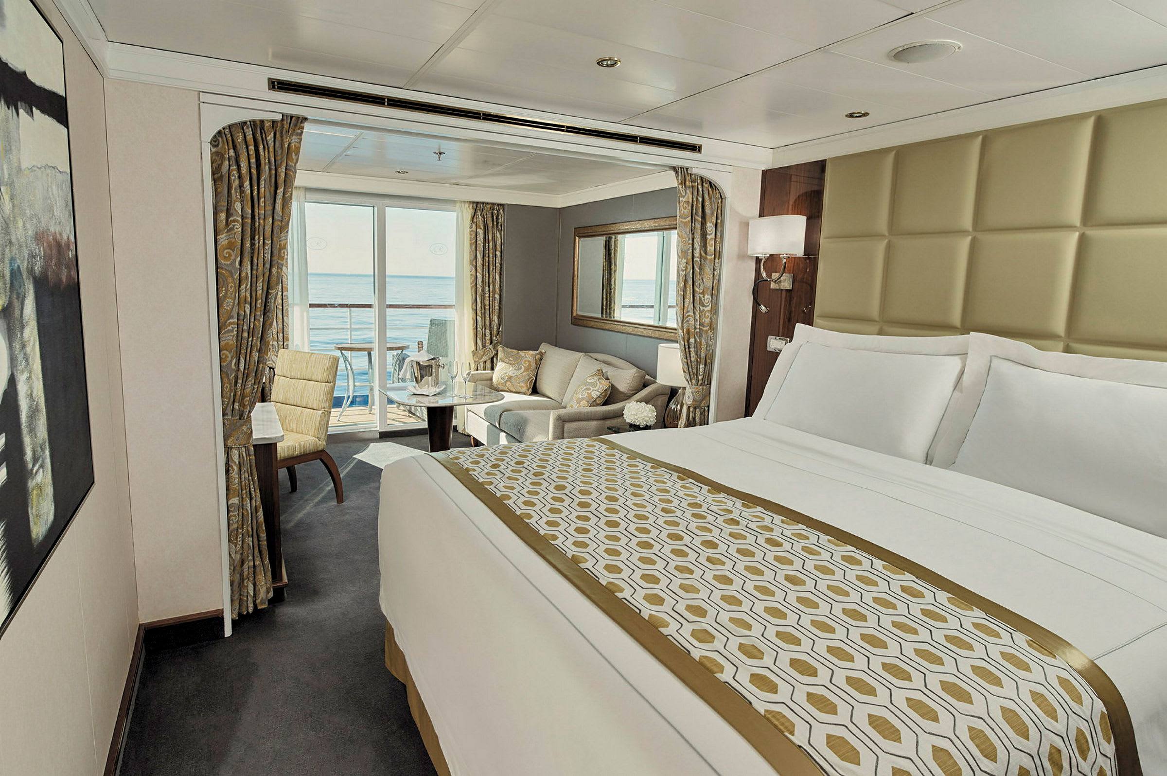 Ett lyxigt hotellrum med stor säng, sittgrupp och balkong med utsikt över havet. (AI-genererad text)