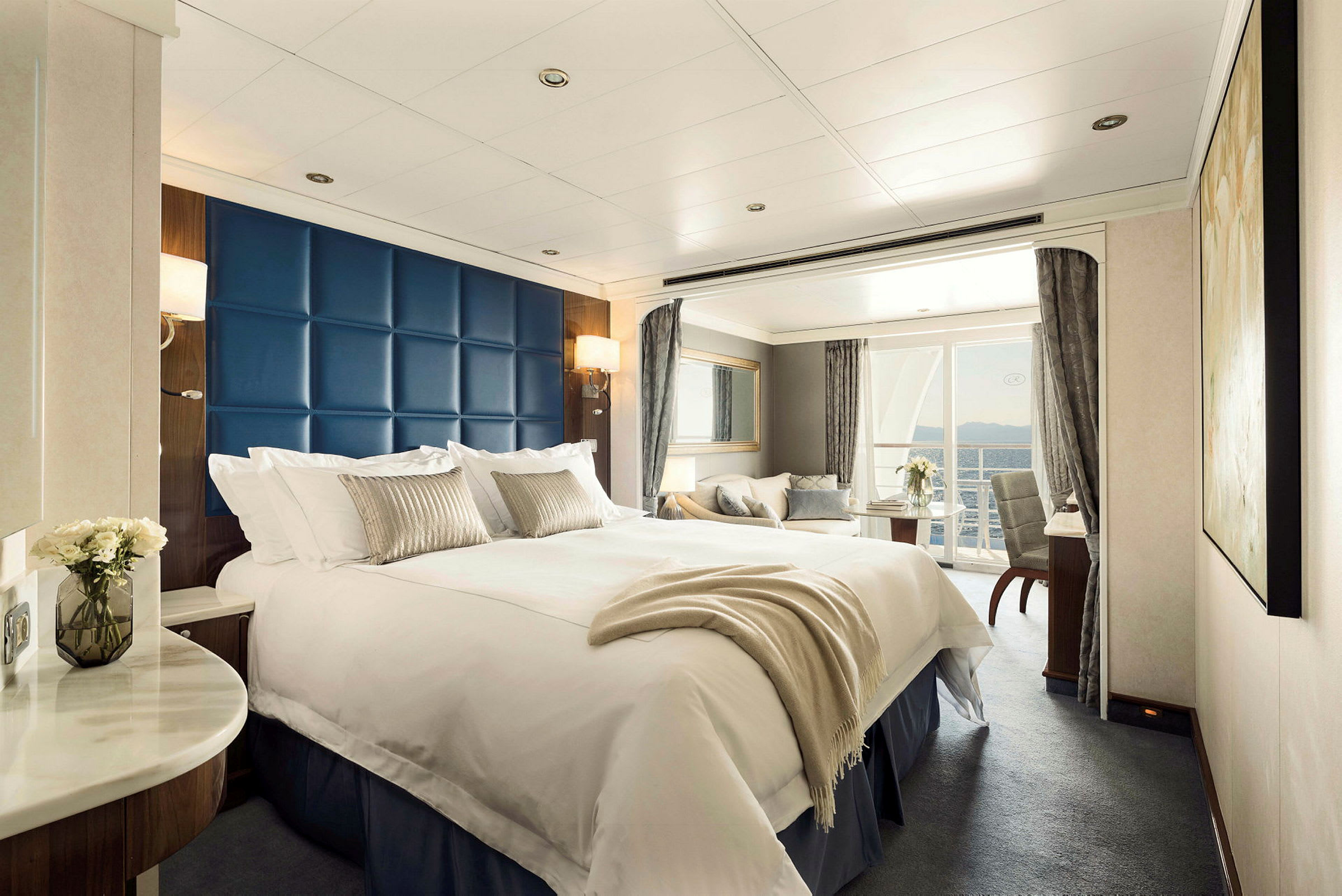 Ett hotellrum med en stor säng, soffhörna och balkong med utsikt. (AI-genererad text)