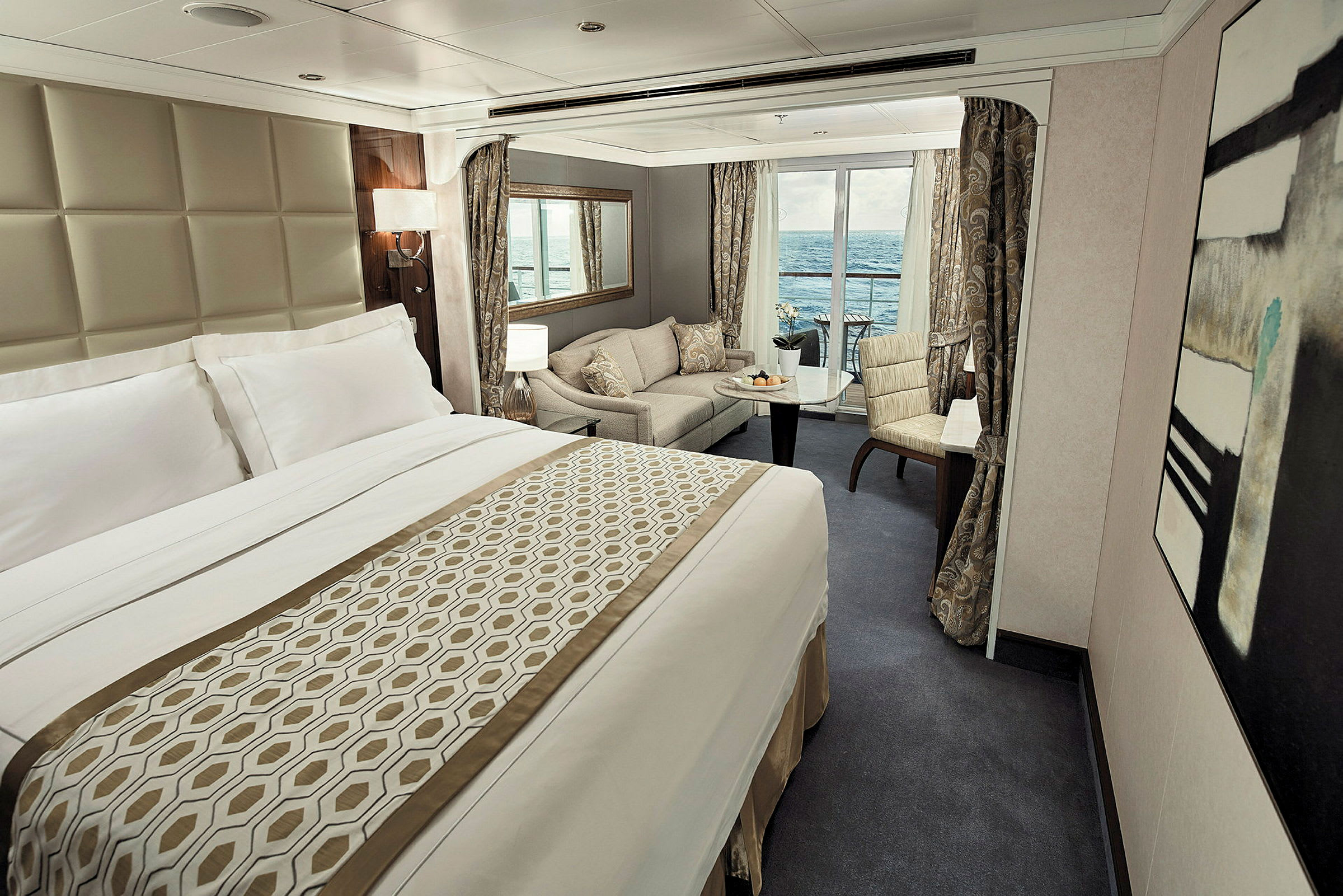 Ett lyxigt hotellrum med en stor säng, sittgrupp, och utsikt över havet från balkongen. (AI-genererad text)