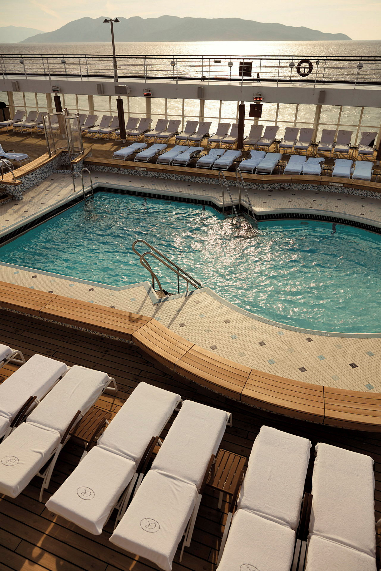 Poolområde på ett fartyg med solstolar och utsikt över havet. (AI-genererad text)
