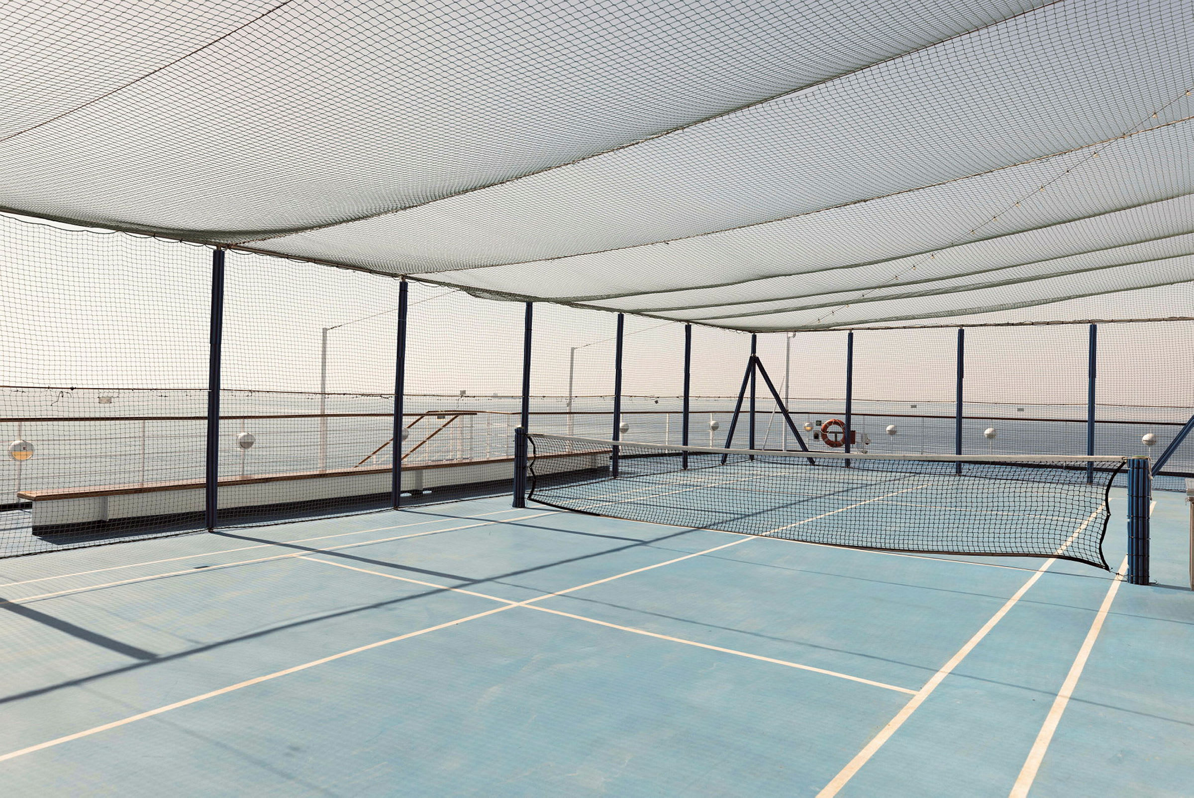 Tennisbana med nät och skyddsnät omkring. (AI-genererad text)