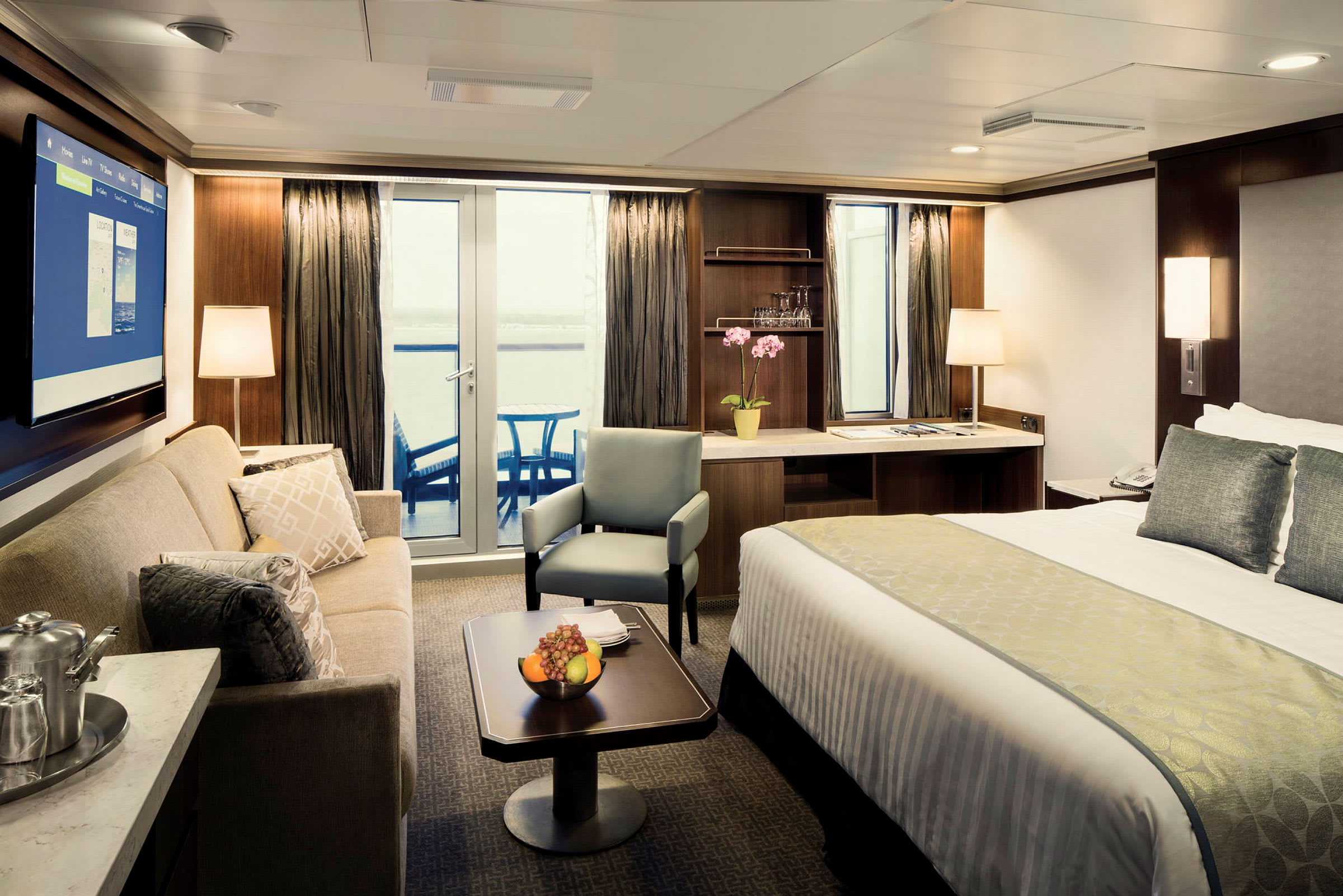 En modern och välmöblerad hotellsvit med en säng, soffa, och stolar. Rummet har en balkong med glasdörrar. (AI-genererad text)
