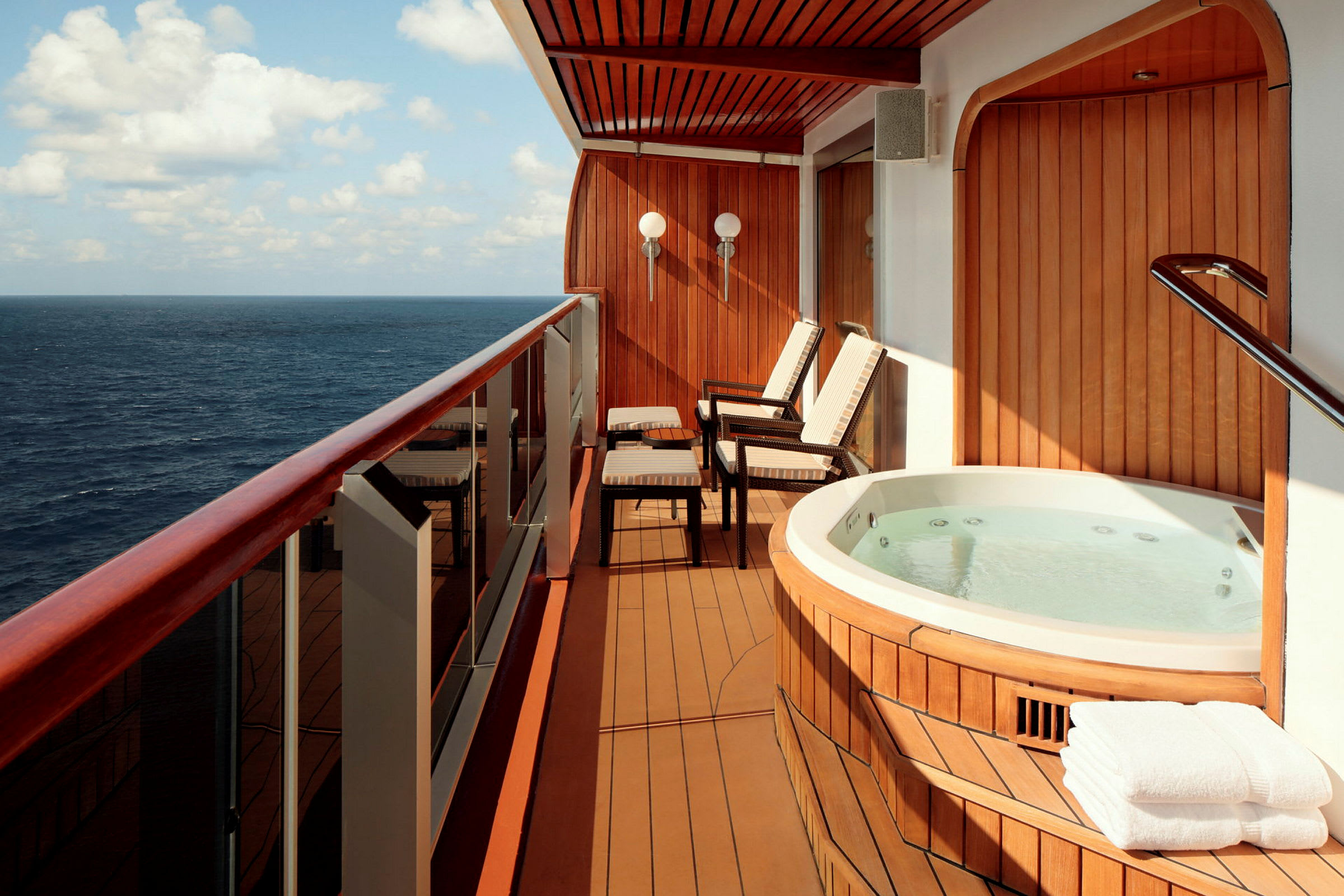 En balkong med jacuzzi, stolar och utsikt över havet. (AI-genererad text)
