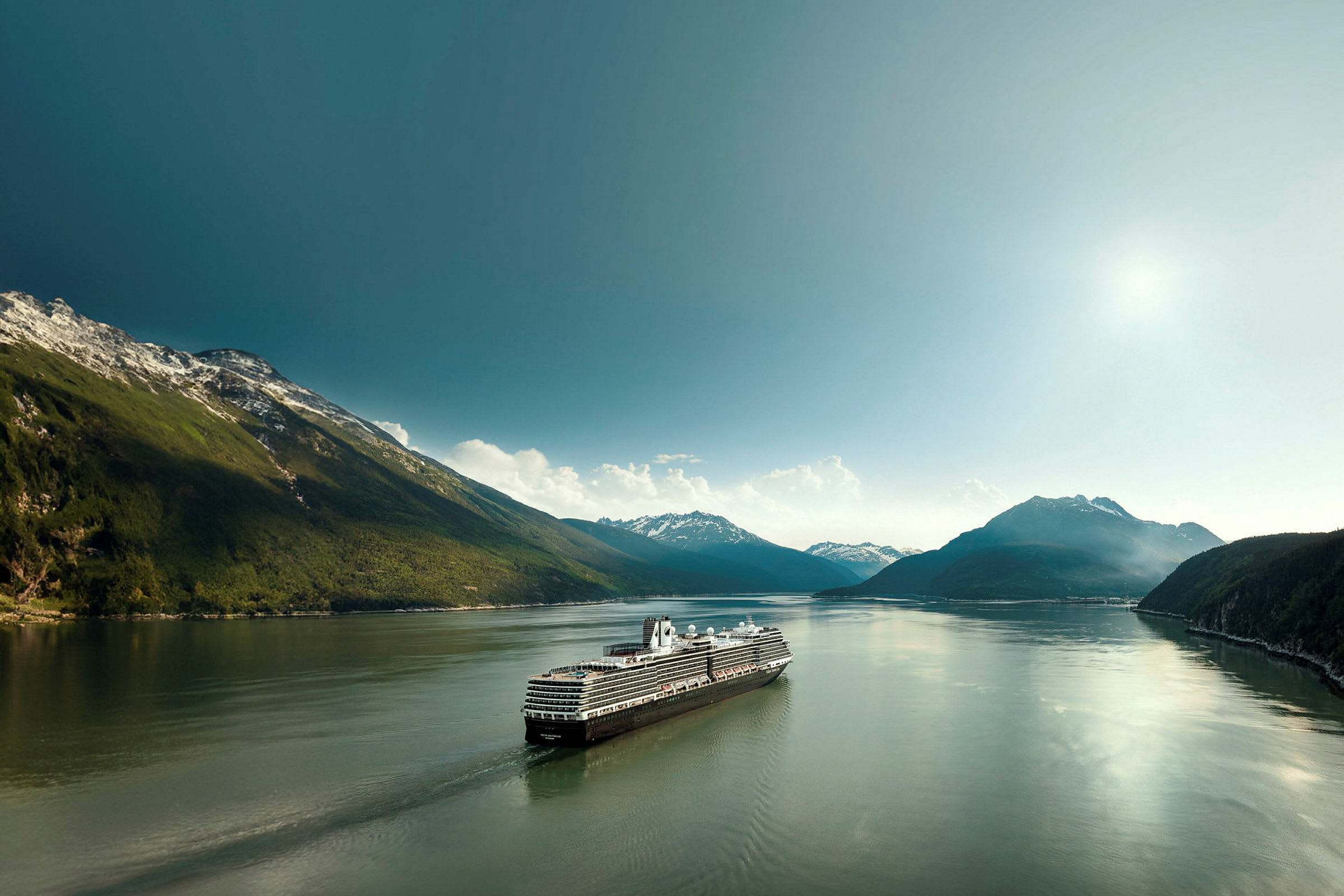 Ett kryssningsfartyg seglar genom en lugn fjord omgiven av berg. (AI-genererad text)