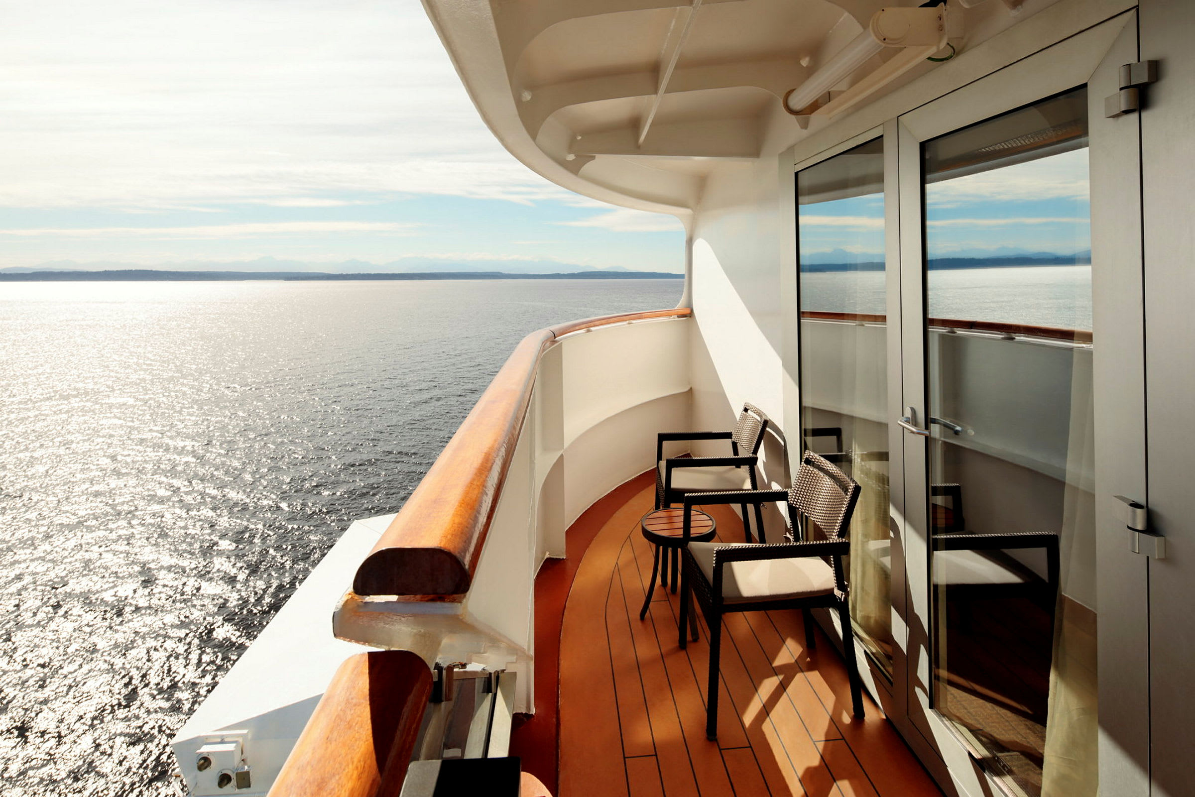 Balkong med två sittplatser och bord med utsikt över havet. (AI-genererad text)