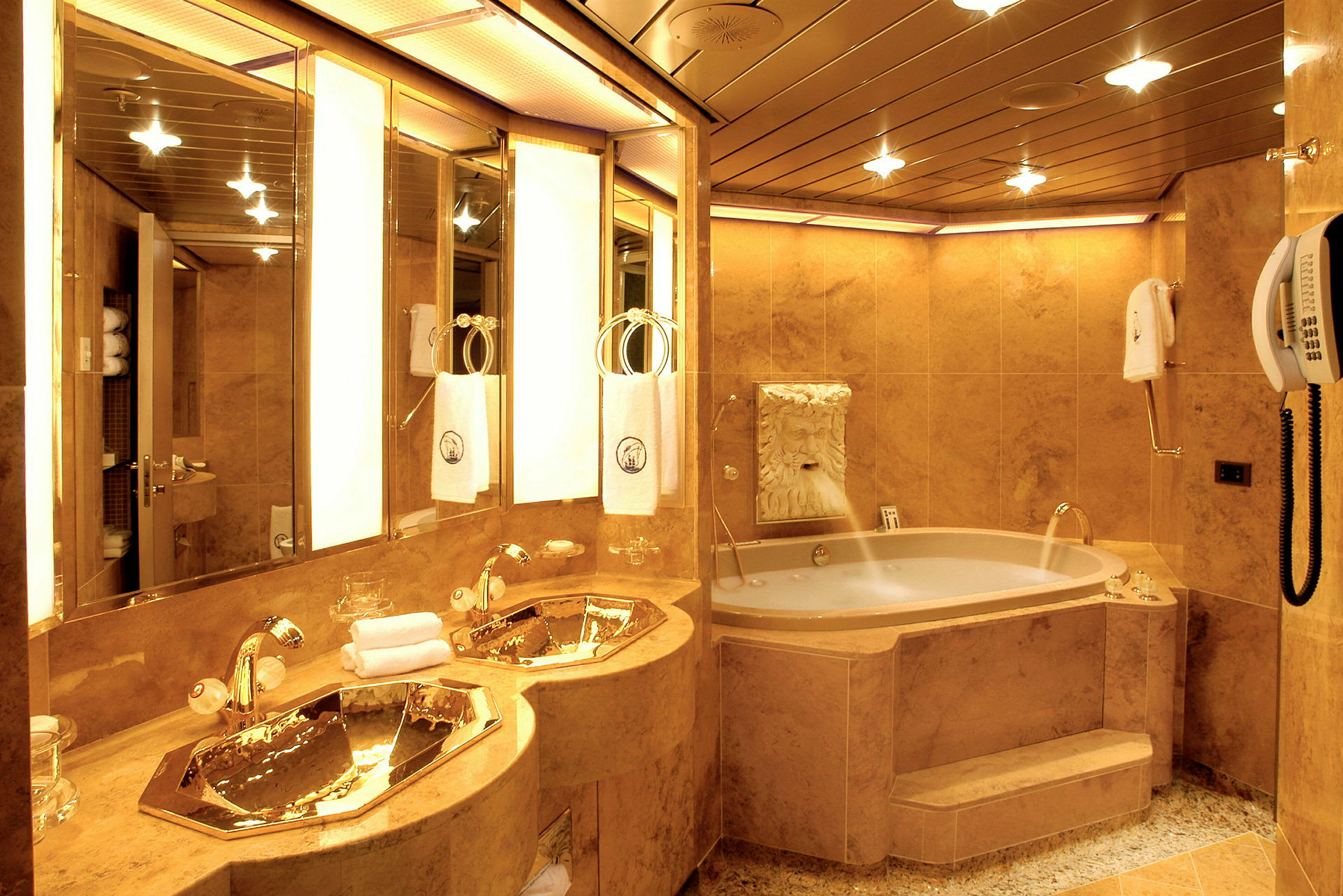 Ett lyxigt badrum med gyllene detaljer på handfat och kranar, en jacuzzi och ett väggmonterat lejonhuvuduttag. (AI-genererad text)