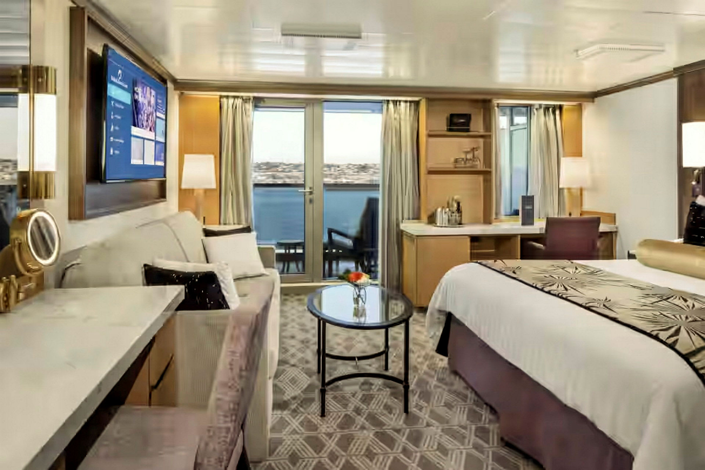 Ett elegant inrett hotellrum med en säng, soffa, bord och en balkong med utsikt över vattnet. (AI-genererad text)