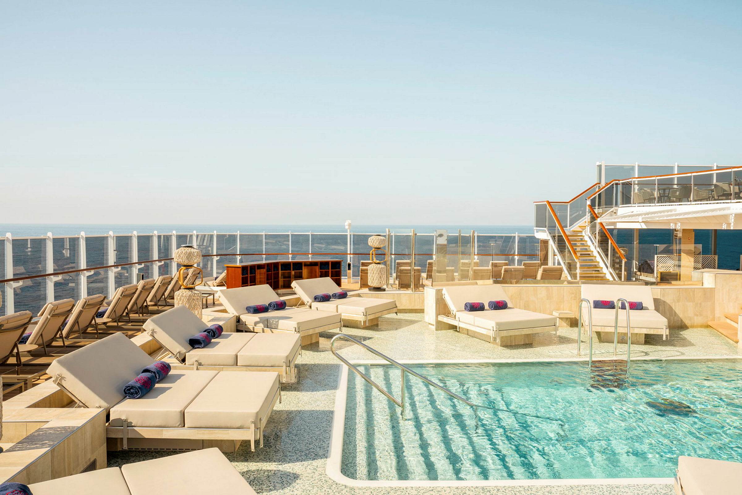 Solstolar och en pool på ett fartygsdäck med havet i bakgrunden. (AI-genererad text)