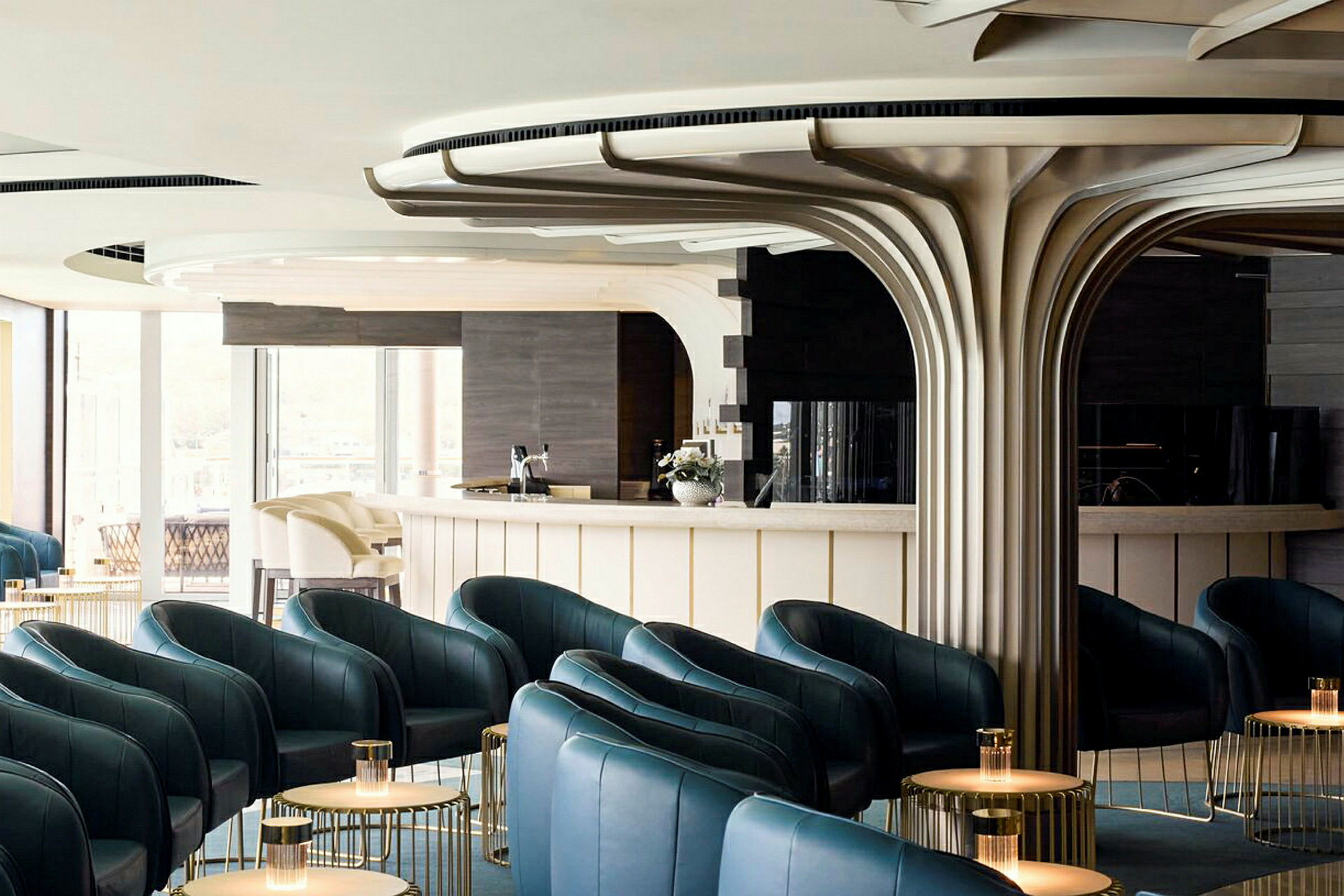 En elegant lounge med mörkgröna fåtöljer, bord med små lampor och en modern designad bar. (AI-genererad text)
