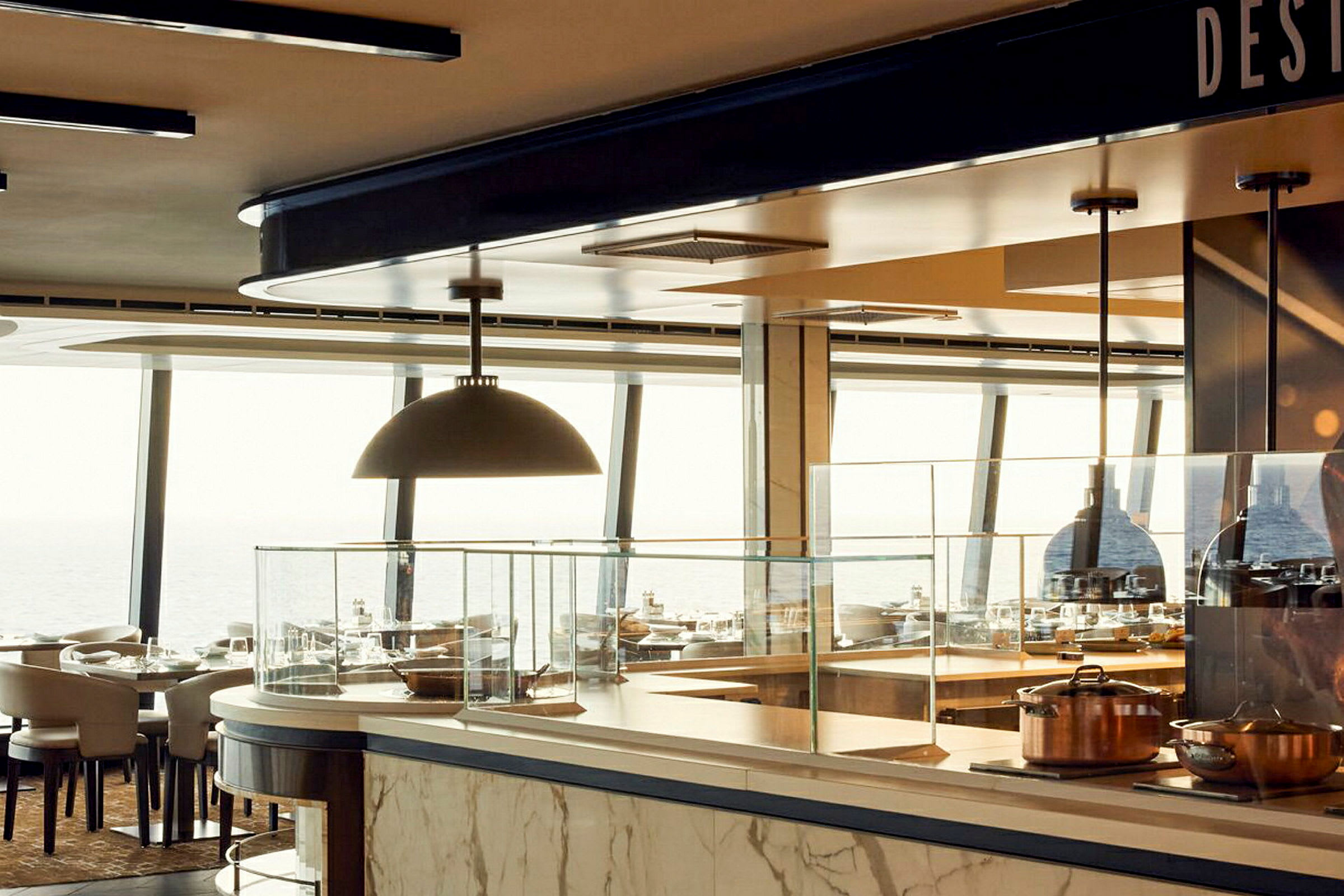 Inomhusutsikt av ett modernt restaurangkök med stora panoramafönster och matbord i bakgrunden. (AI-genererad text)