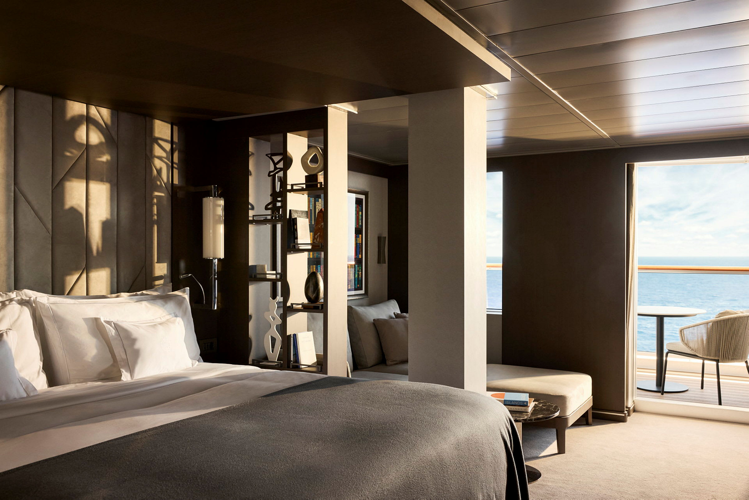 Ett modernt hotellrum med en dubbelsäng, ljusa textilier och en utsikt över havet från en balkong. (AI-genererad text)