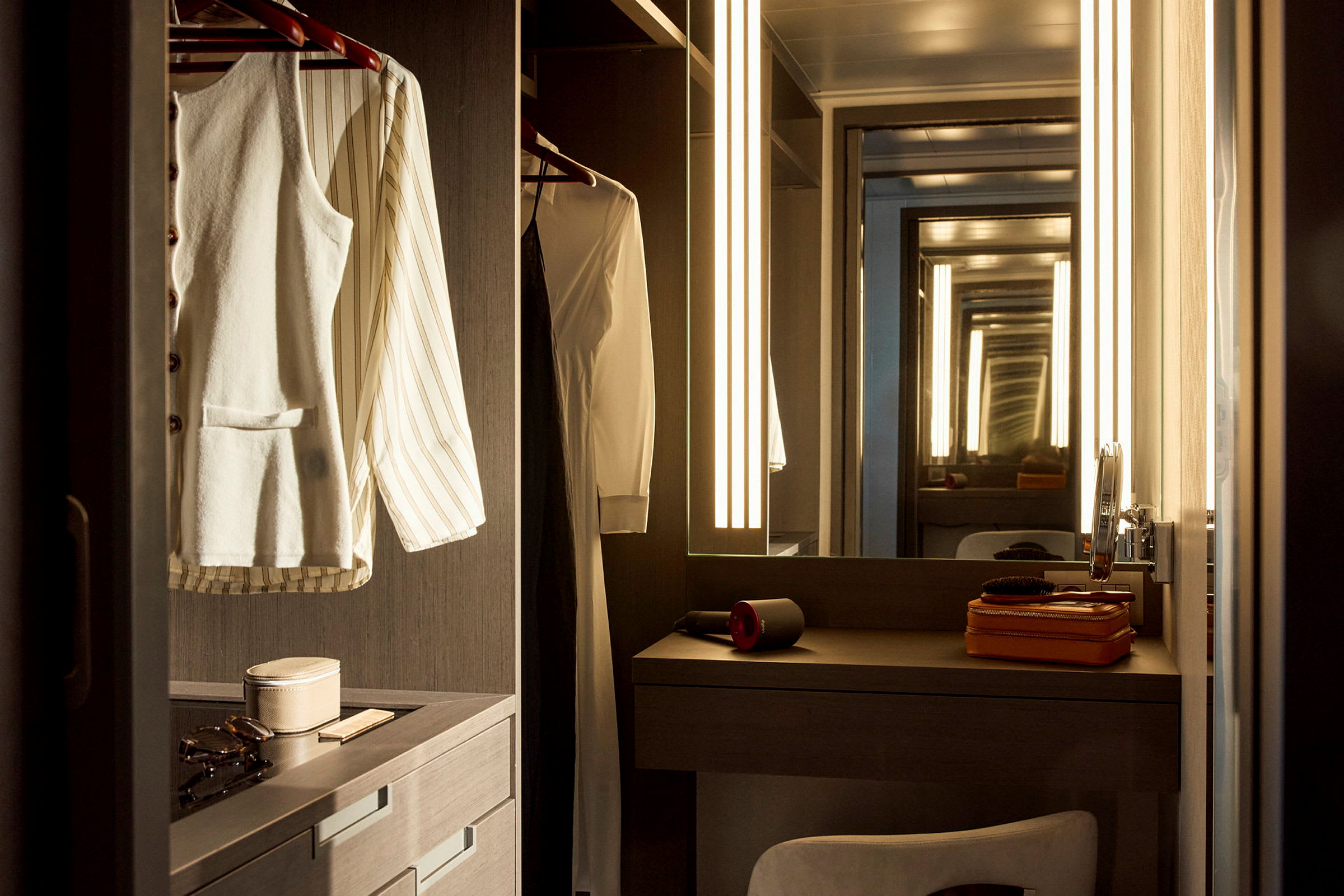 Bild av ett elegant hotellrum med en garderob och spegel, kläder hängande och toalettartiklar på hyllan. (AI-genererad text)