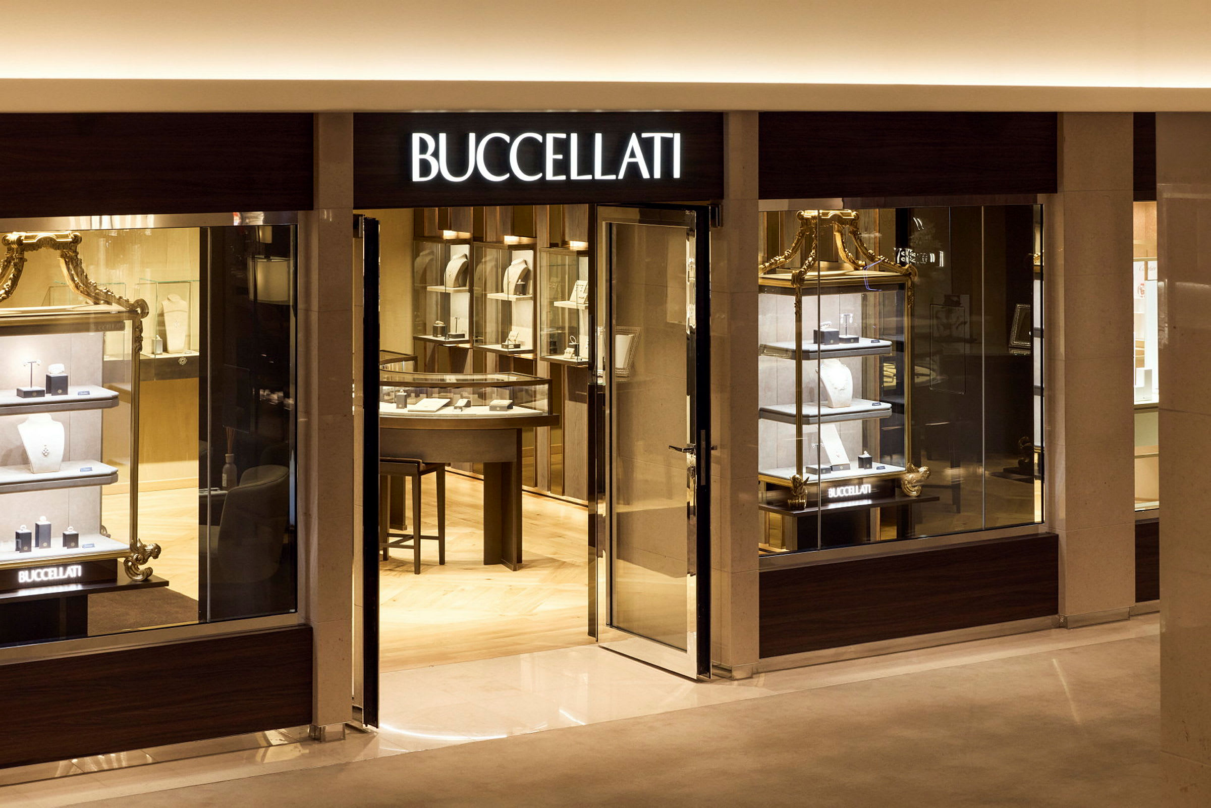 Butiksfront med ljusskylt märkt 'Buccellati' och synliga smyckesdisplayer. (AI-genererad text)