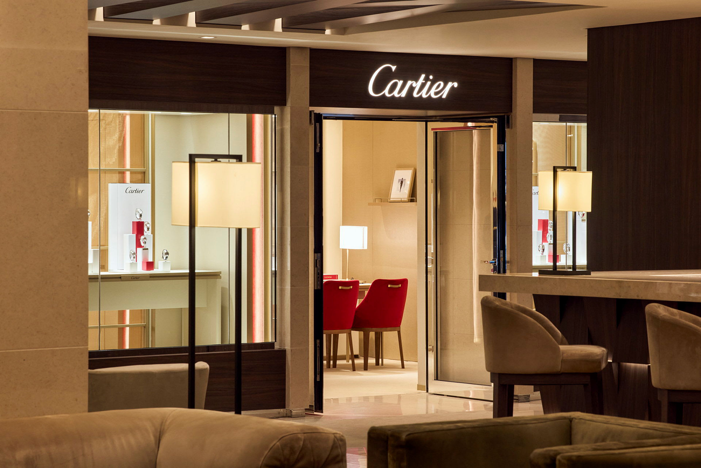 Butik med varumärket Cartier och eleganta möbler med röda stolar. (AI-genererad text)