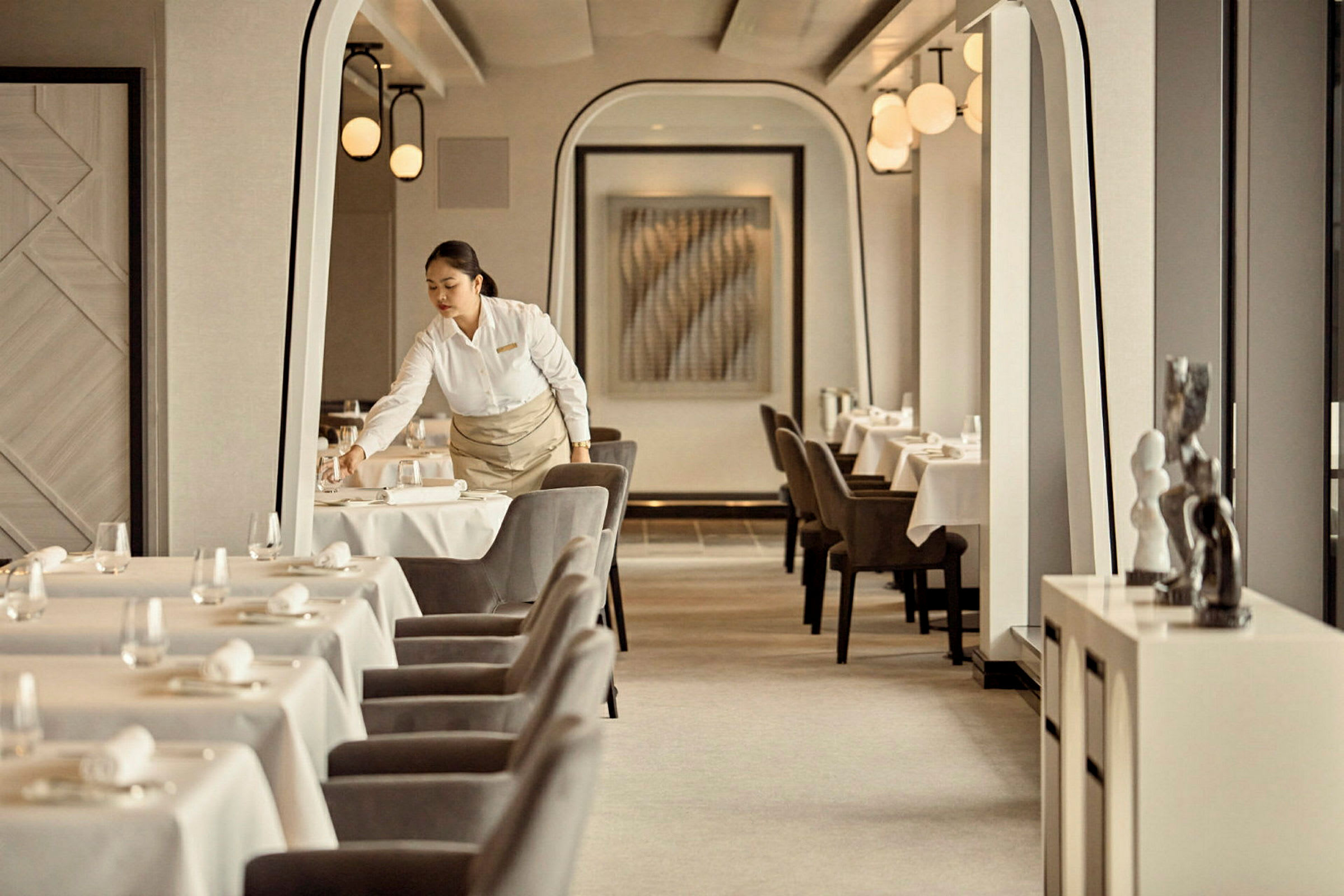 Servitris arrangerar bord i en elegant restaurang. (AI-genererad text)