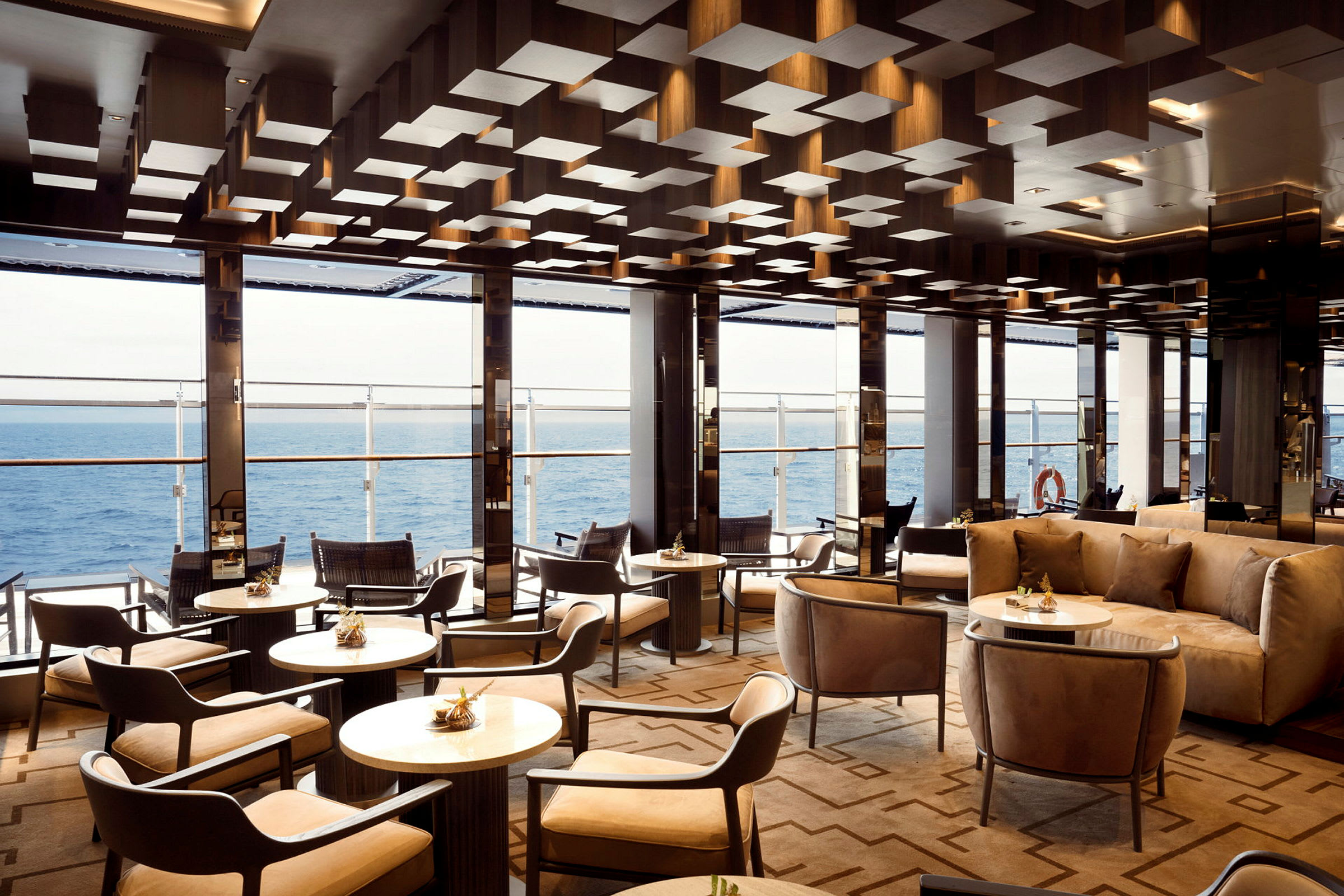 En elegant lounge ombord med bord och stolar samt havsutsikt. (AI-genererad text)