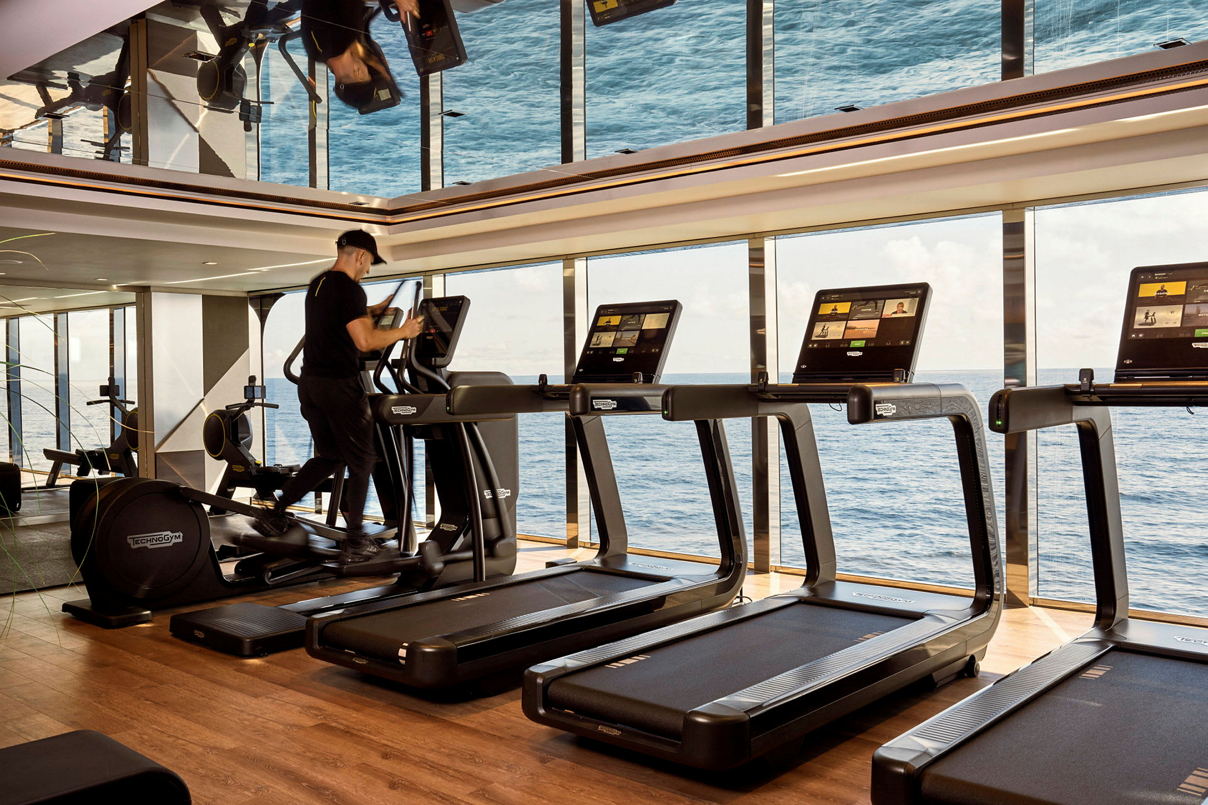 Ett gym med löpband och en havsutsikt genom stora fönster. (AI-genererad text)