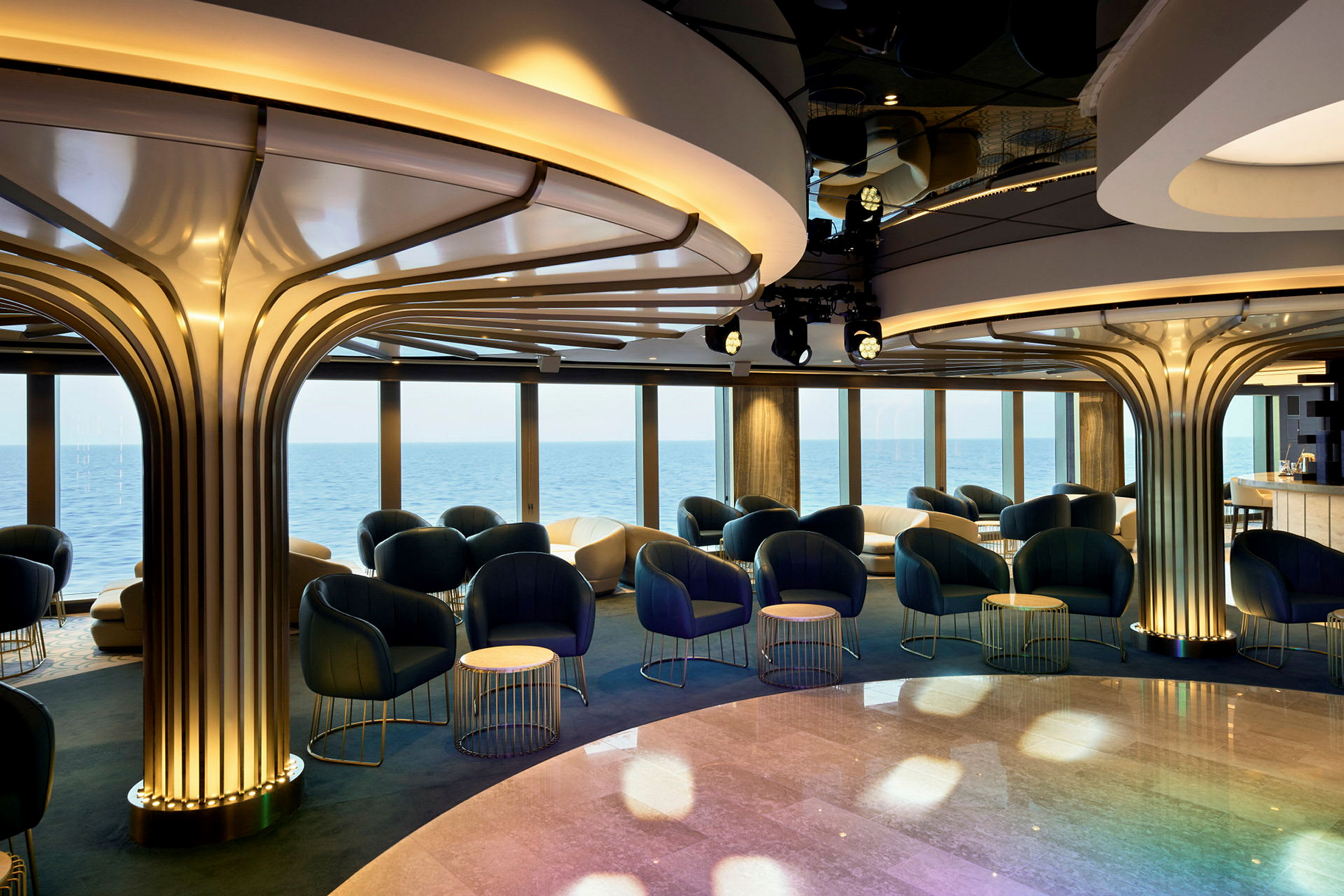 Ett elegant loungeområde med moderna stolar och bord samt panoramafönster med utsikt över havet. (AI-genererad text)