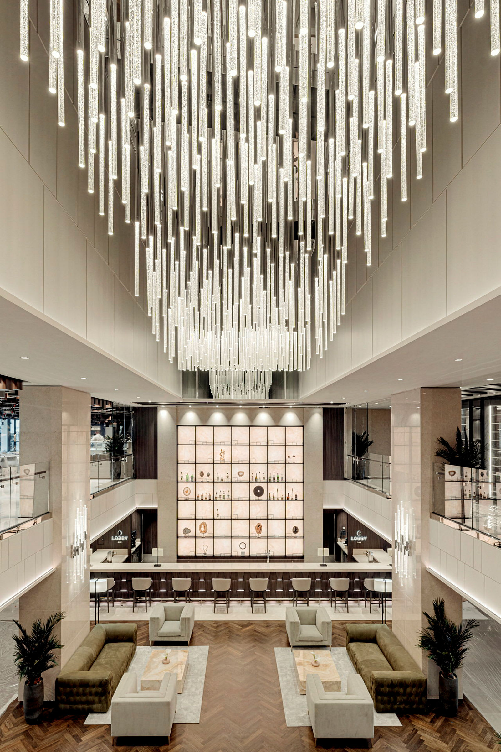 Modern hotellobby med en hängande ljuskrona i taket och möbler i neutrala färger. (AI-genererad text)