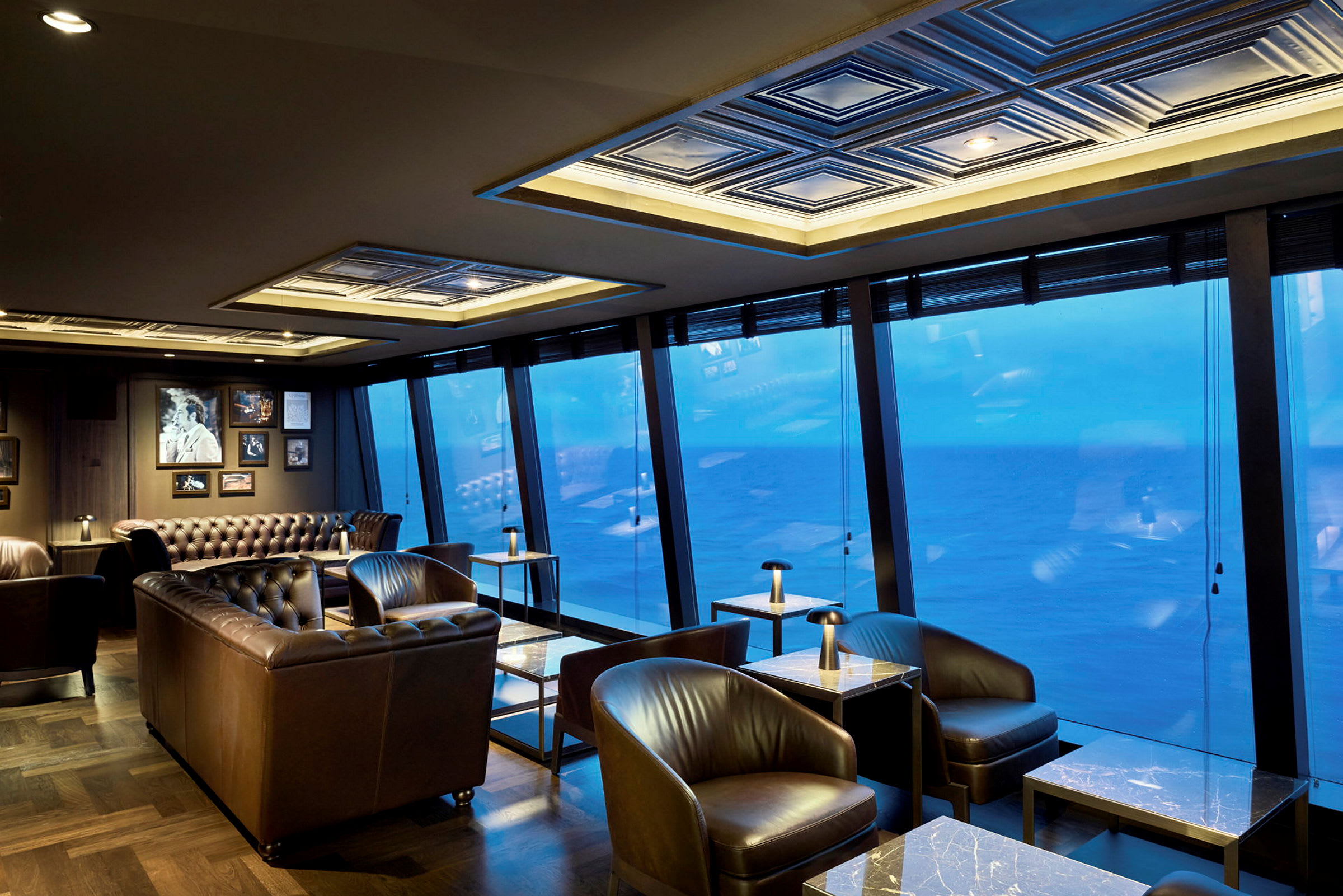 En elegant restaurang med skinnsoffor och marmorbord, med stora fönster som ger utsikt över havet. (AI-genererad text)
