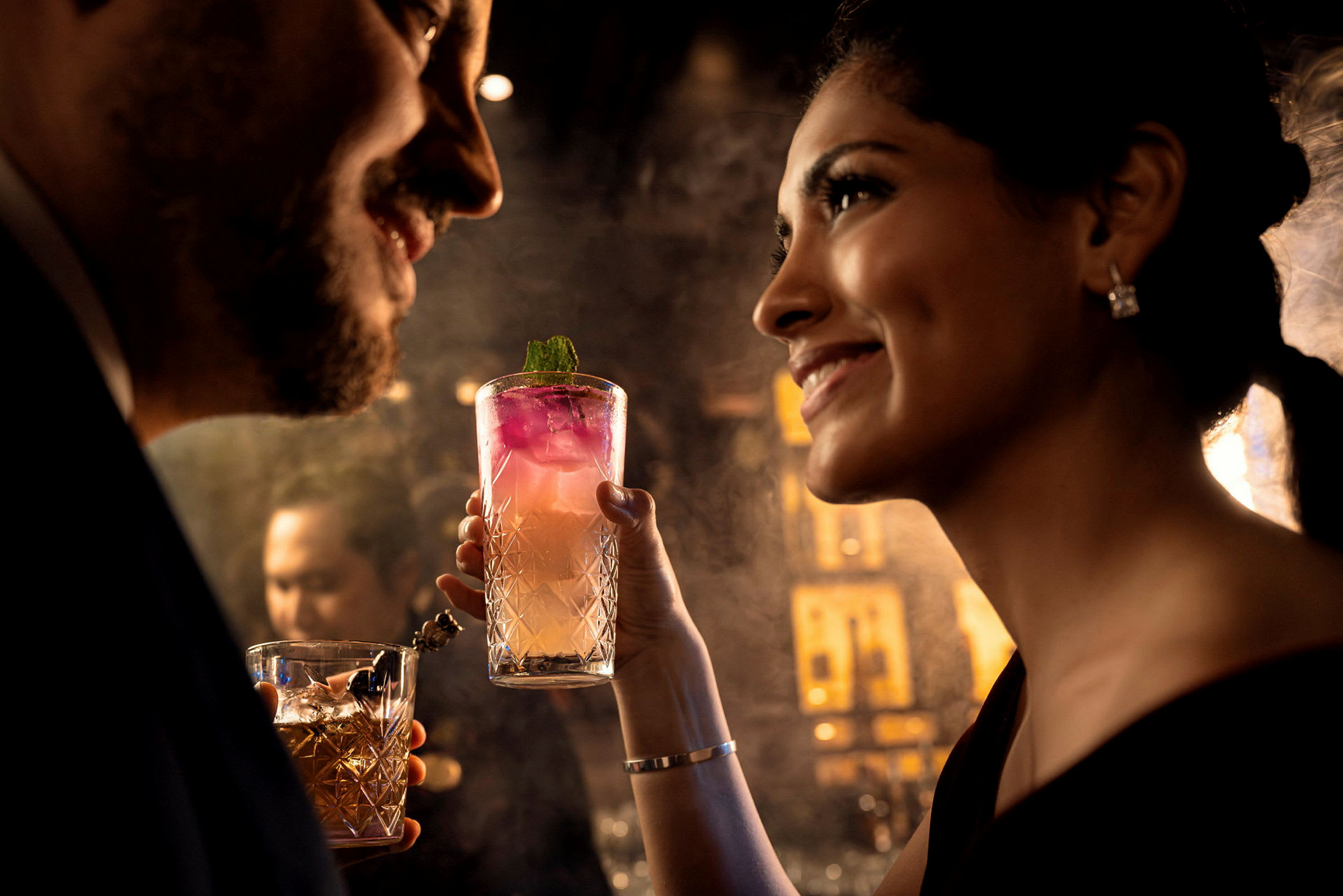 Två personer skålar med varsin cocktail i en elegant atmosfär. (AI-genererad text)